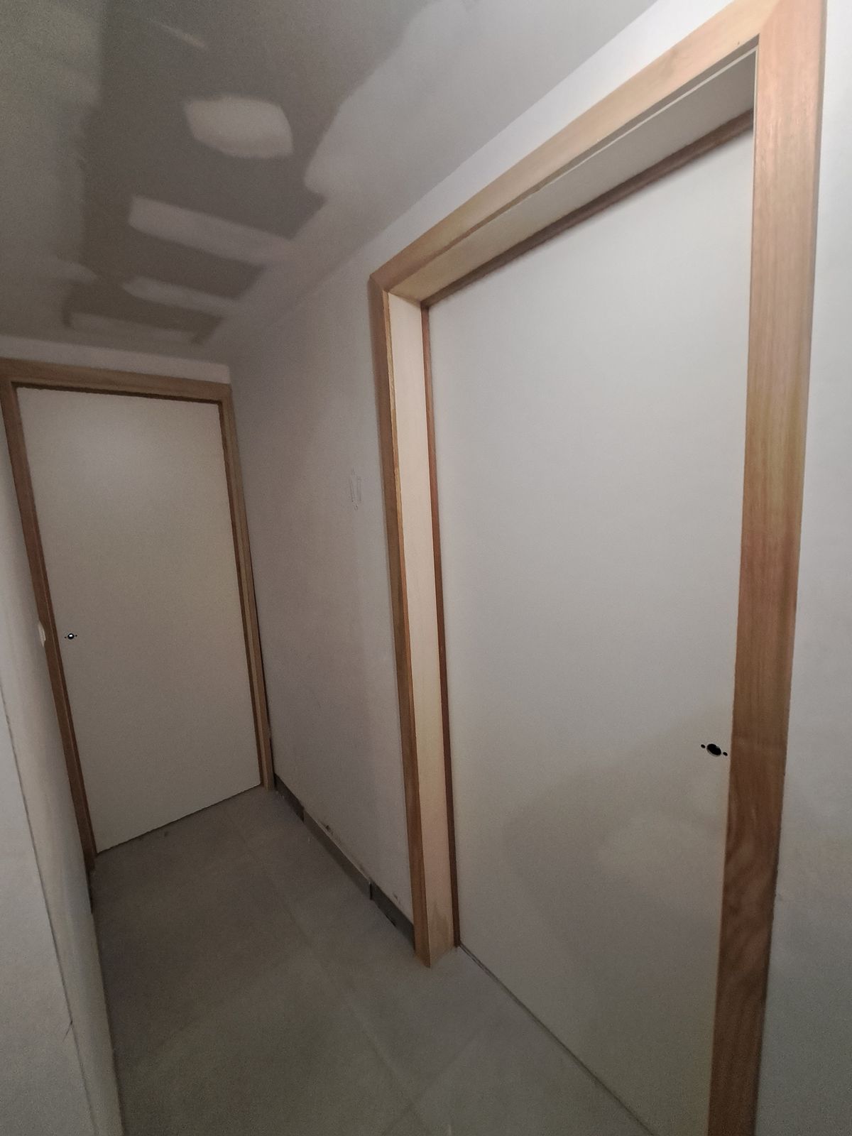 Twee witte binnendeuren met houten kaders in een hal van een nieuwbouwwoning in Hamme.