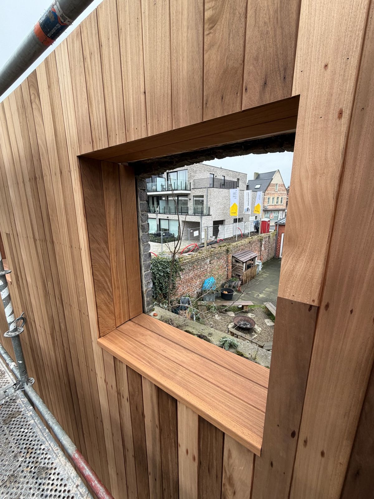 Diep cederhouten raamkader in een houten gevel met uitzicht op de straat in Sint-Kruis.