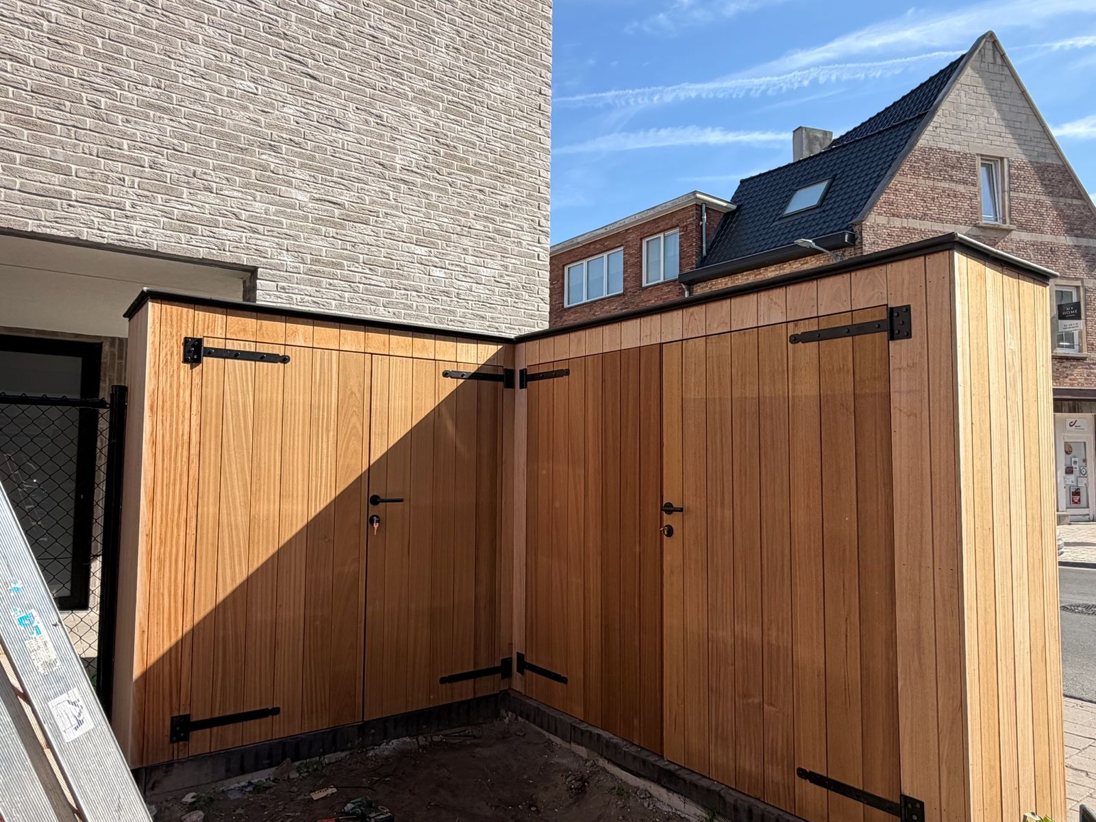 Cederhouten bergingen met dubbele deuren en zwart hang en sluitwerk op een terras in Sint-Kruis.
