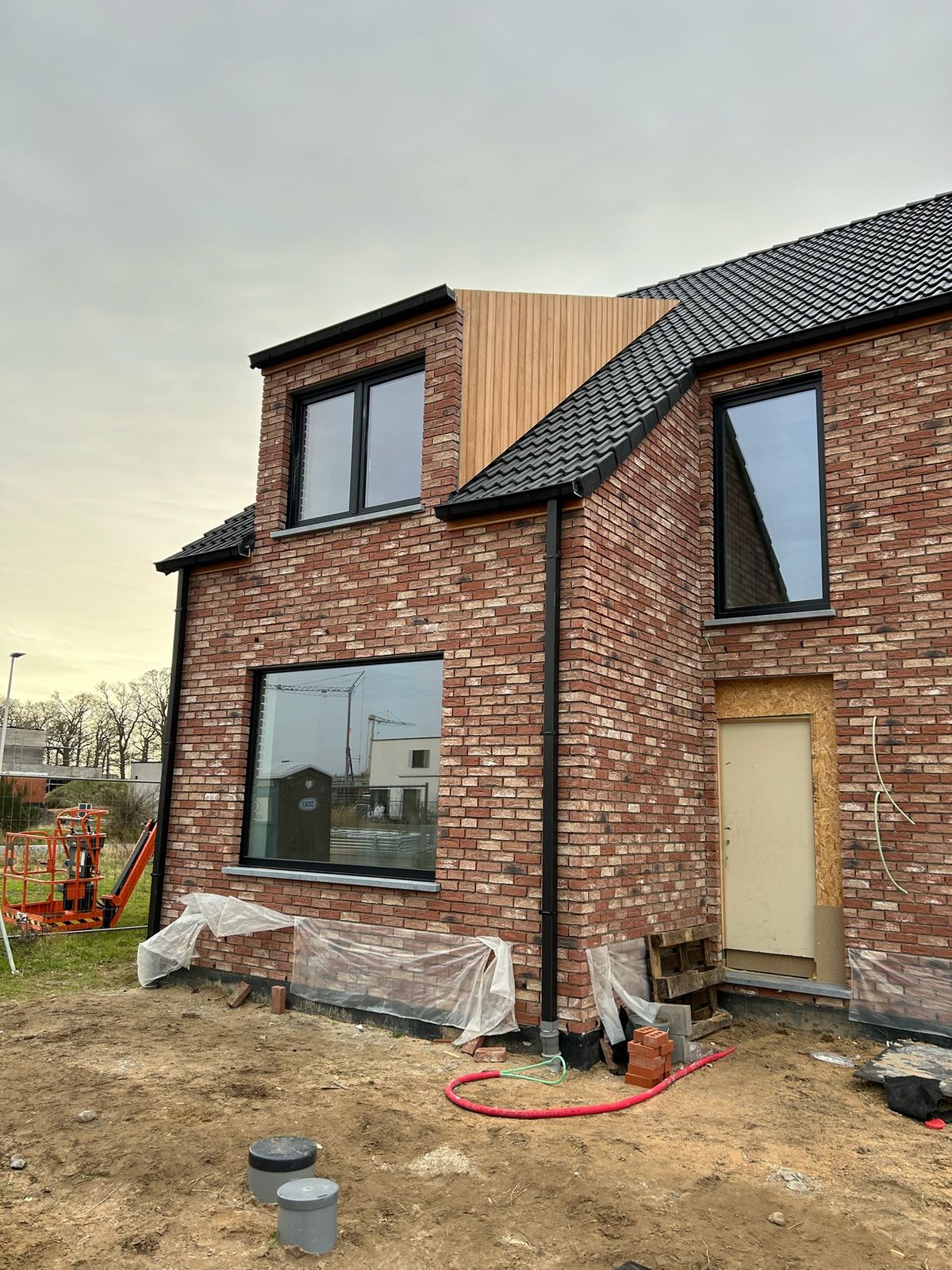 Nieuwbouwwoning met houten bekleding op de dakkapel tijdens de werken in Varsenare.