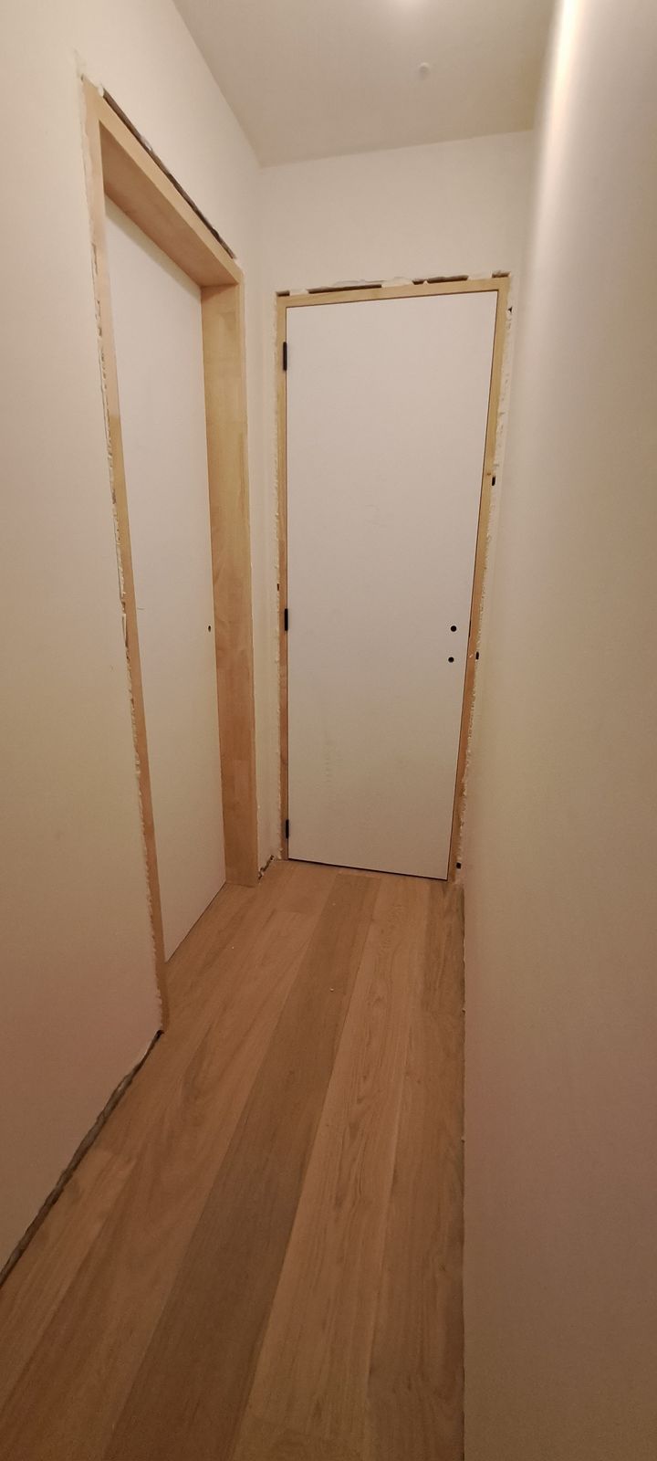 Gang met eiken parket en een witte binnendeur aan het einde in Beveren-Leie.