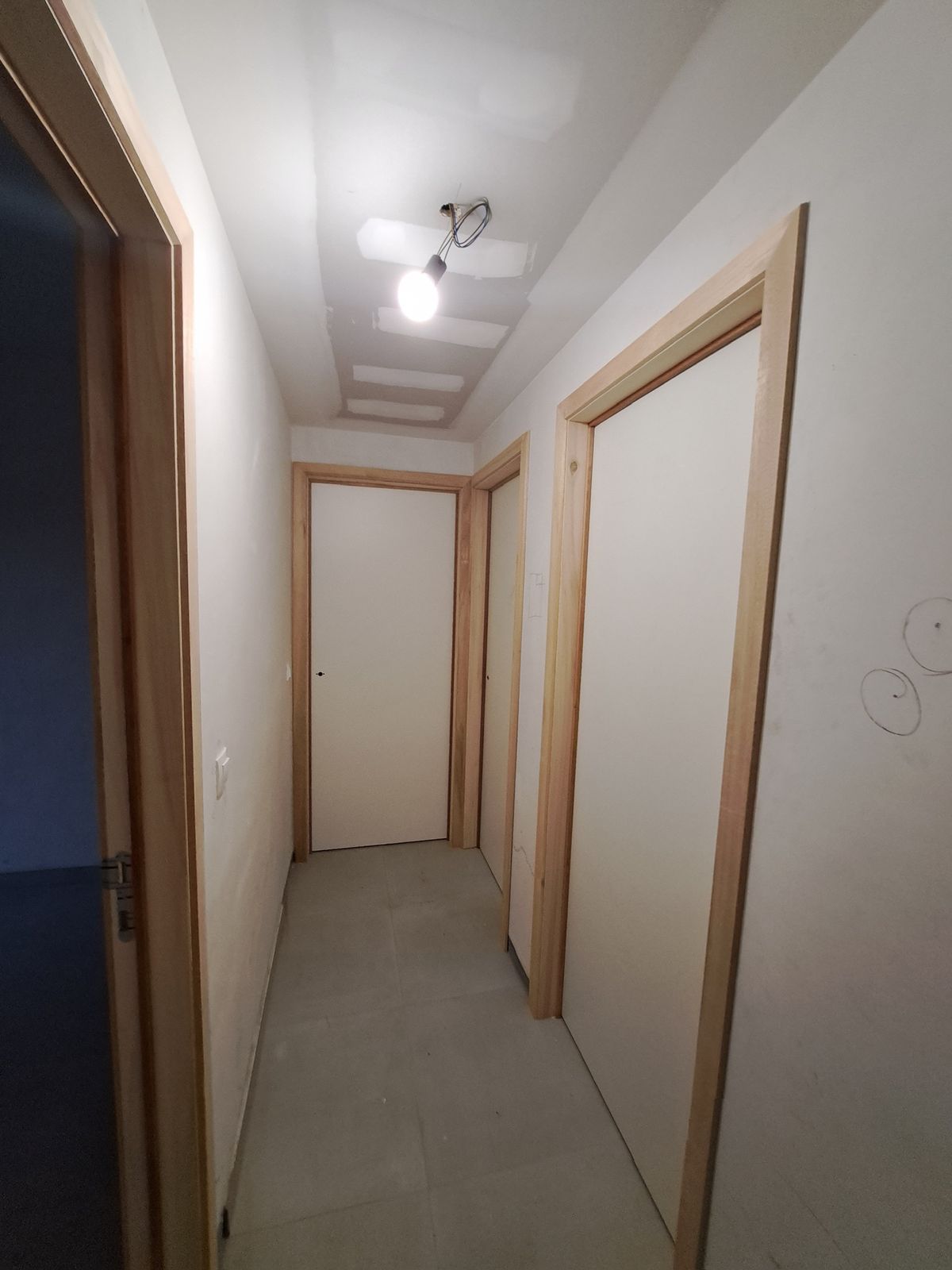 Gang met meerdere witte binnendeuren en houten omlijstingen in een woning in Hamme.