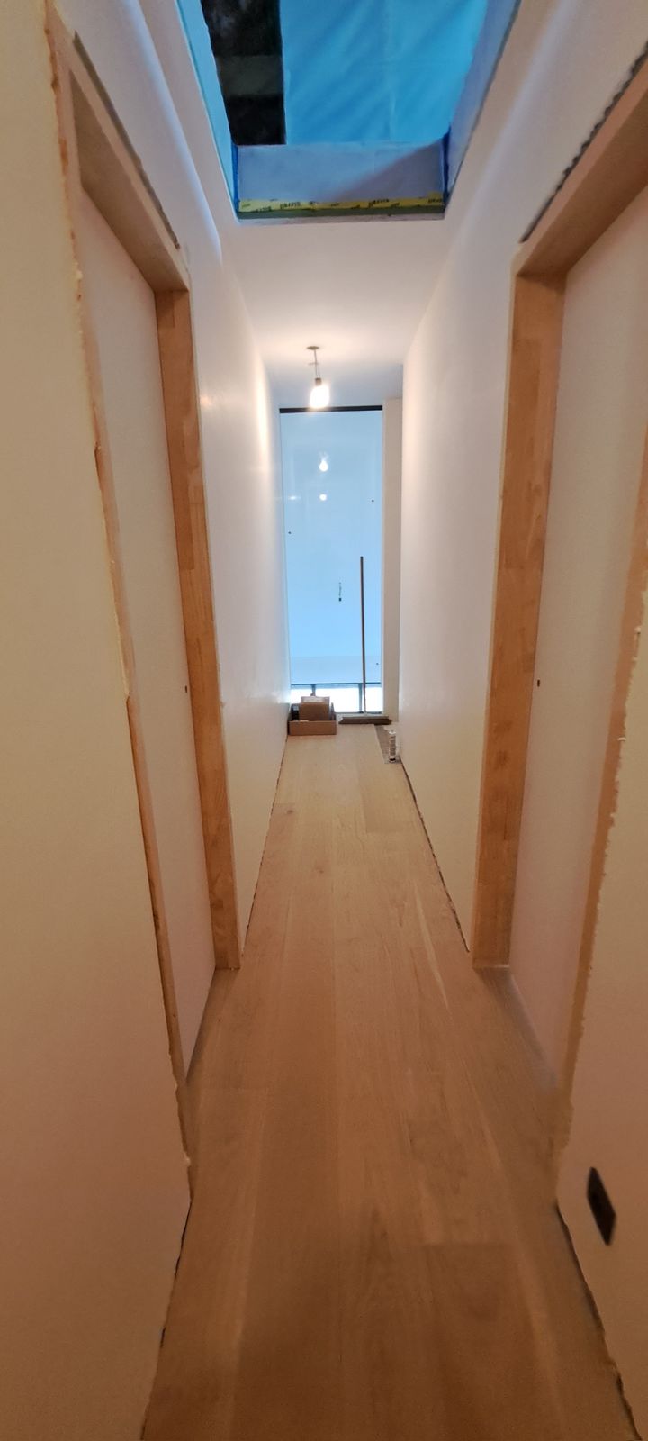 Lange gang met eiken parketvloer en daglicht via een dakraam in Beveren-Leie.