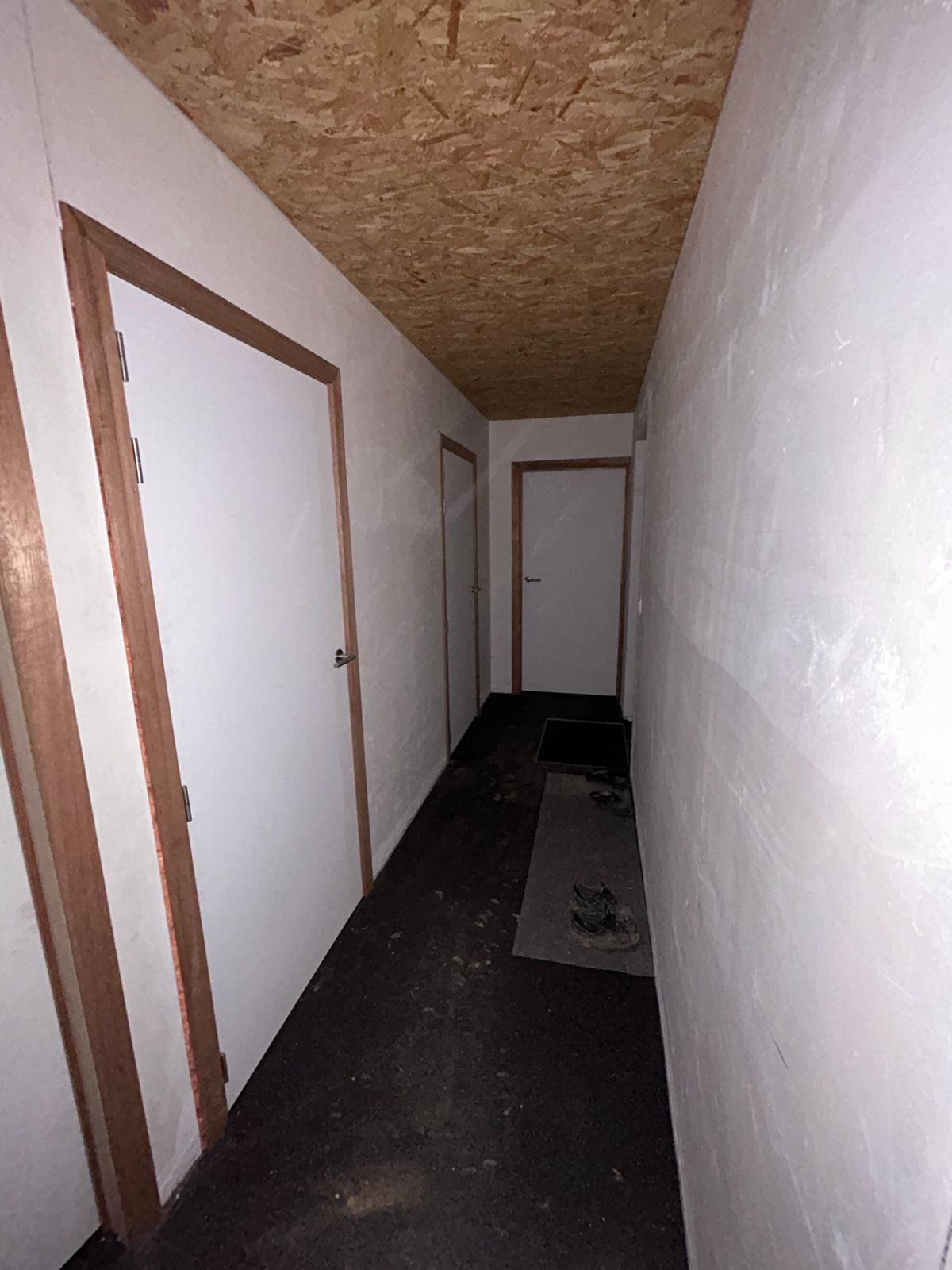 Gang met meerdere witte binnendeuren en houten kaders in een woning in Lendelede.