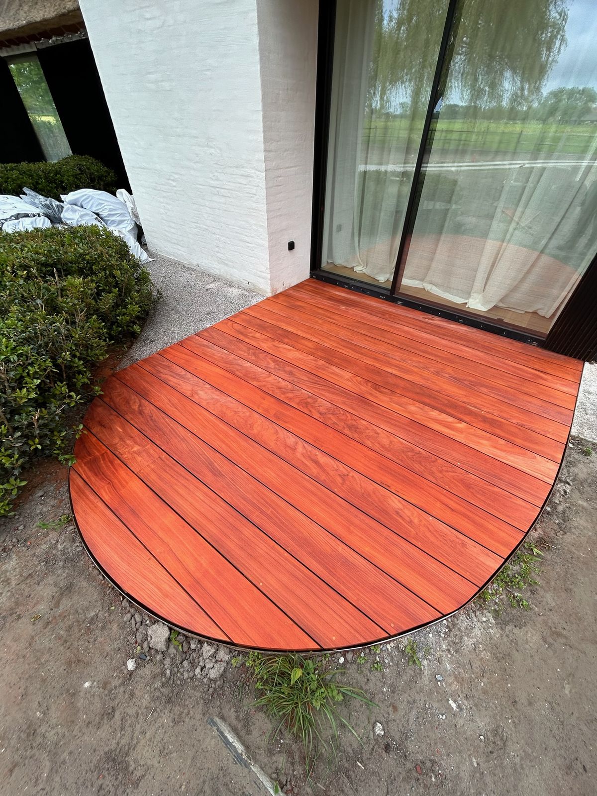 Klein hardhouten terras met afgeronde rand voor een schuifraam in Oostkerke.