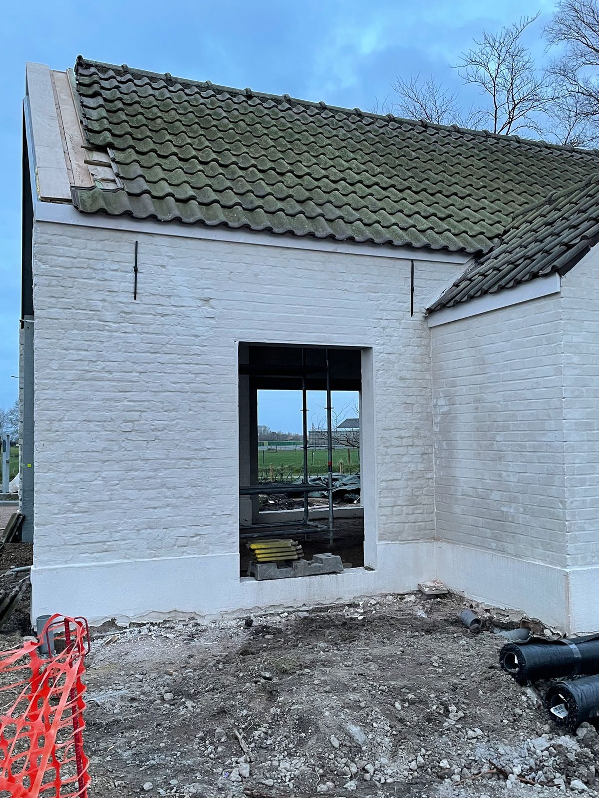 Witgeschilderde gevel van de gerenoveerde schuur met nieuw raam in Eernegem.