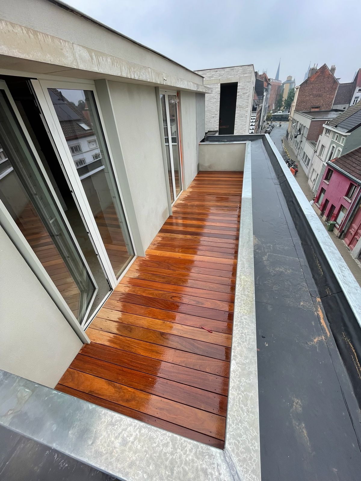 Hardhouten terrasplanken op een smal balkon met zicht over de daken in Gent.