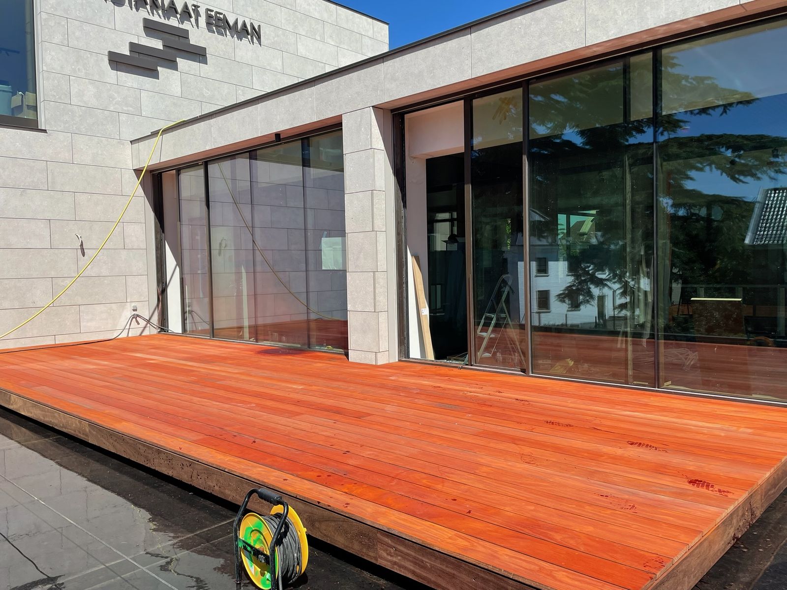 Hardhouten terras voor de grote glazen pui van een modern gebouw in Gent.