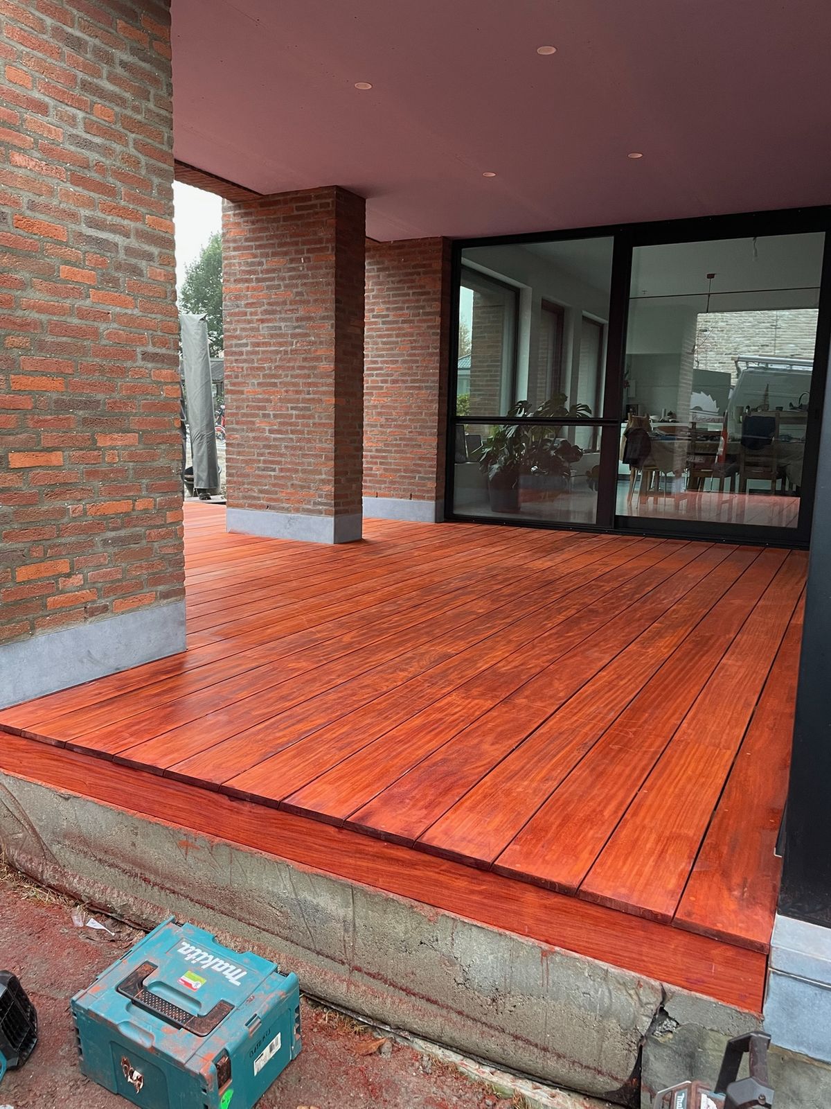 Nieuw rood hardhouten terras onder een overdekte gevel met grote ramen in Bazel.
