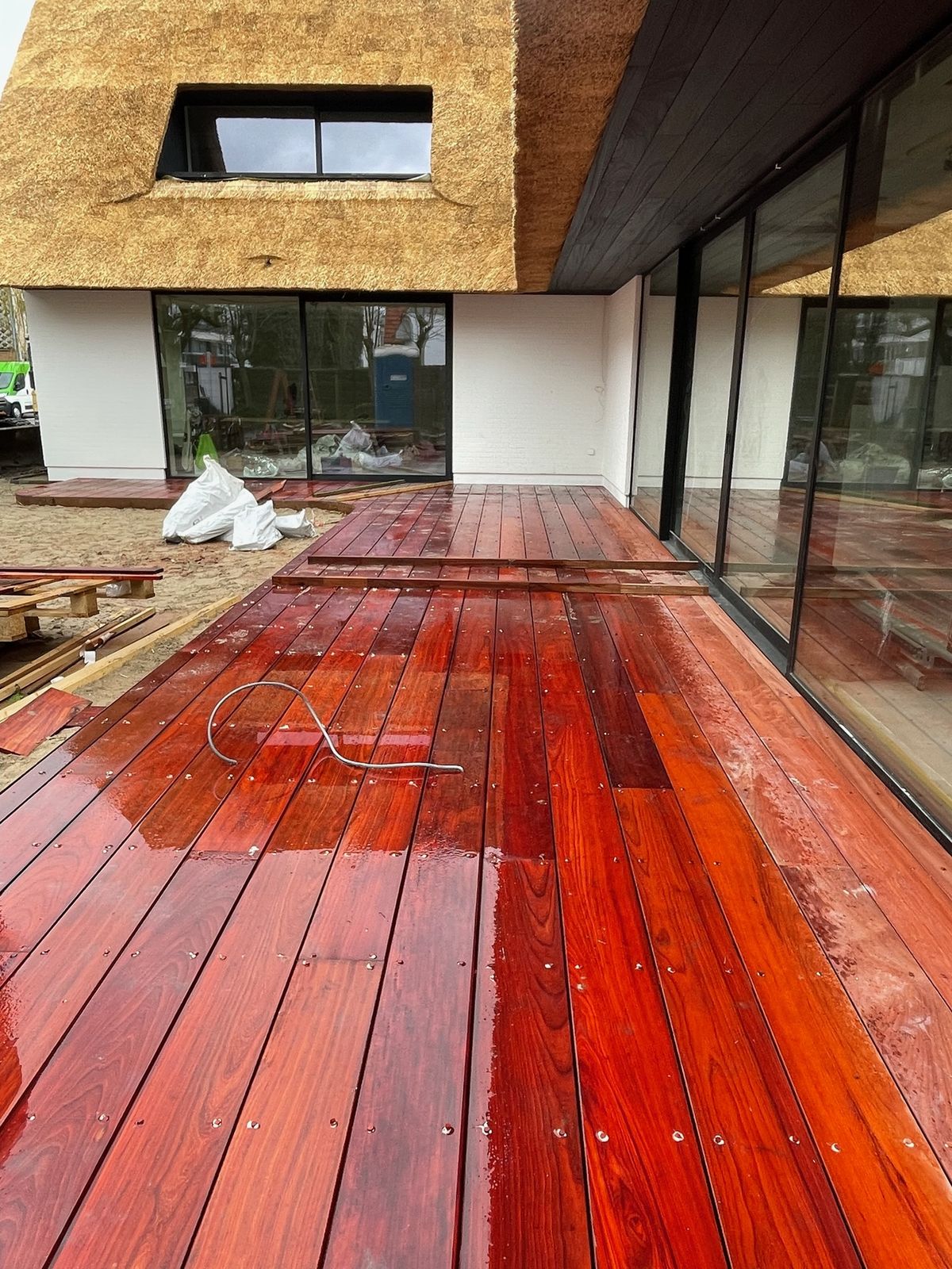 Nat geolied hardhouten terras langs de glazen gevel van een villa in Knokke-Heist.