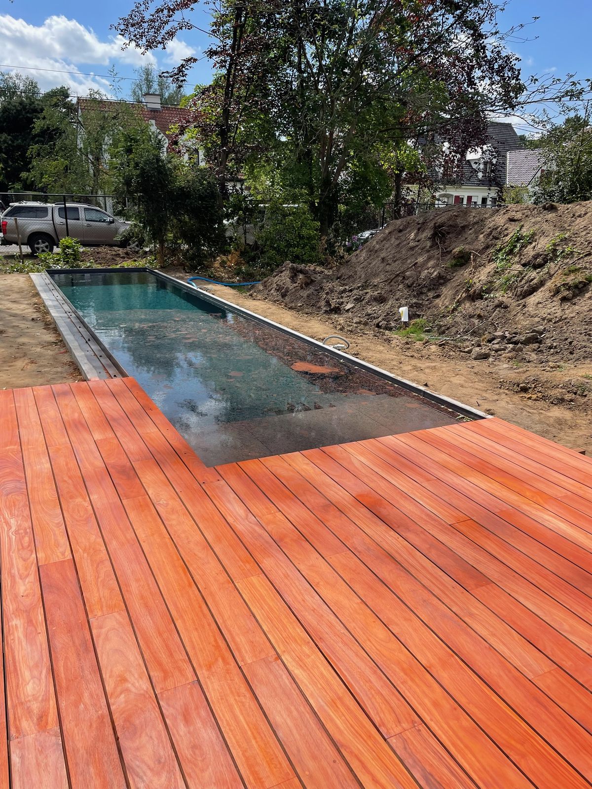 Nieuw gelegd hardhouten terras aan de rand van een langwerpig zwembad in De Pinte.