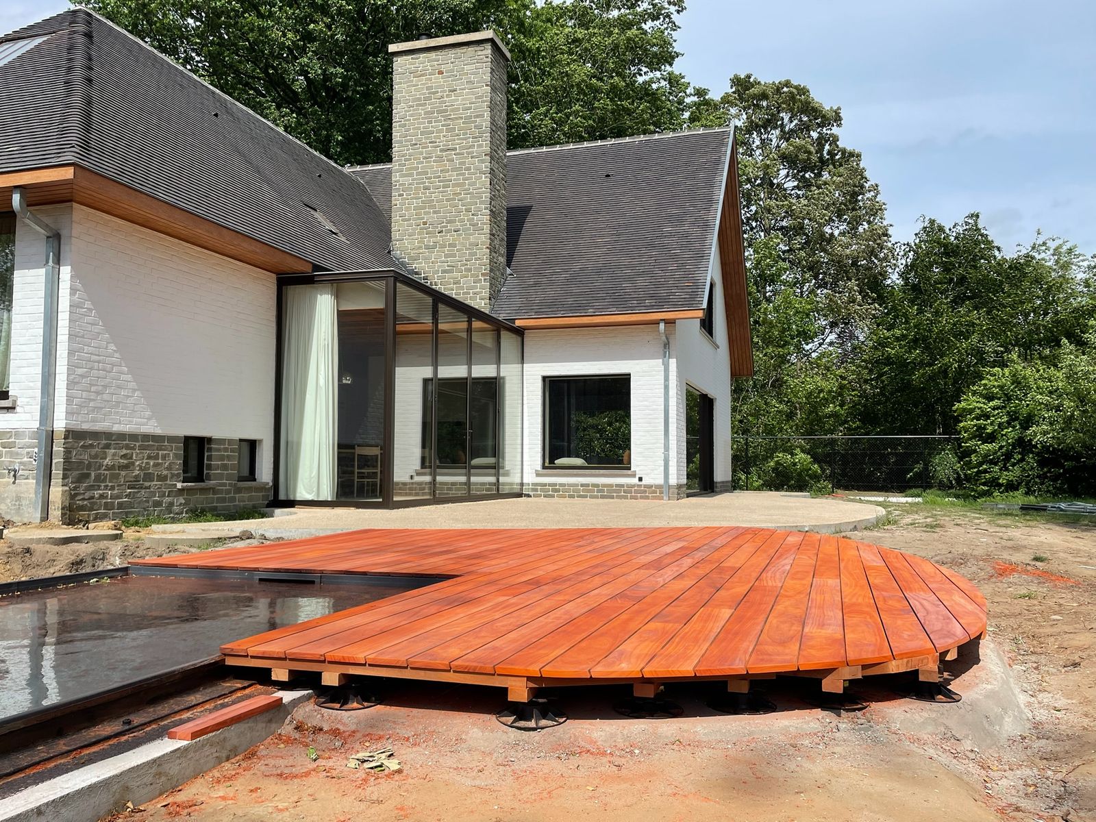 Hardhouten terras met afgeronde vorm aan een zwembad achter een villa in De Pinte.