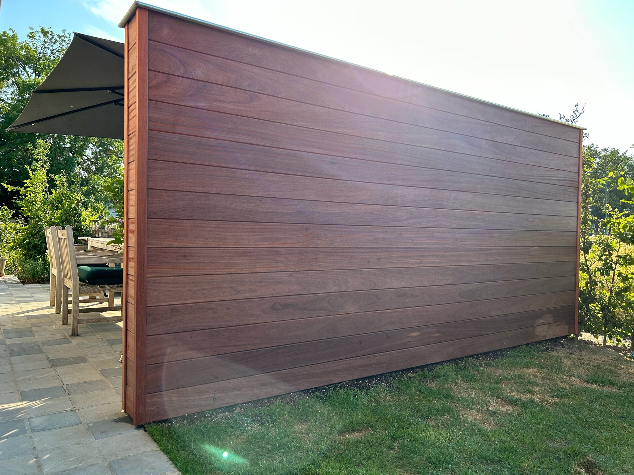 Hardhouten tuinscherm met horizontale planken naast een terras
