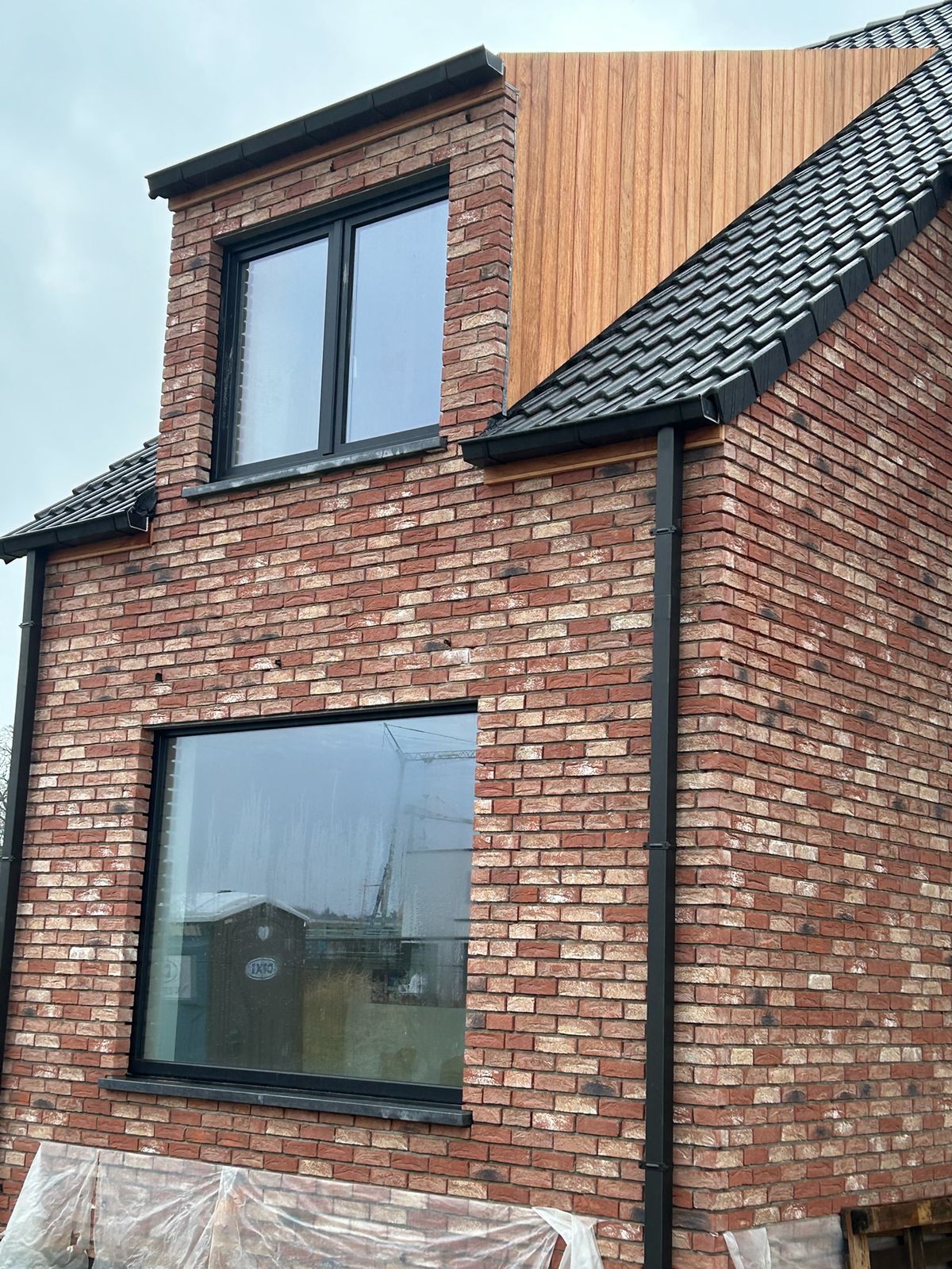 Houten bekleding op de zijwangen van een dakkapel in een bakstenen woning in Varsenare.