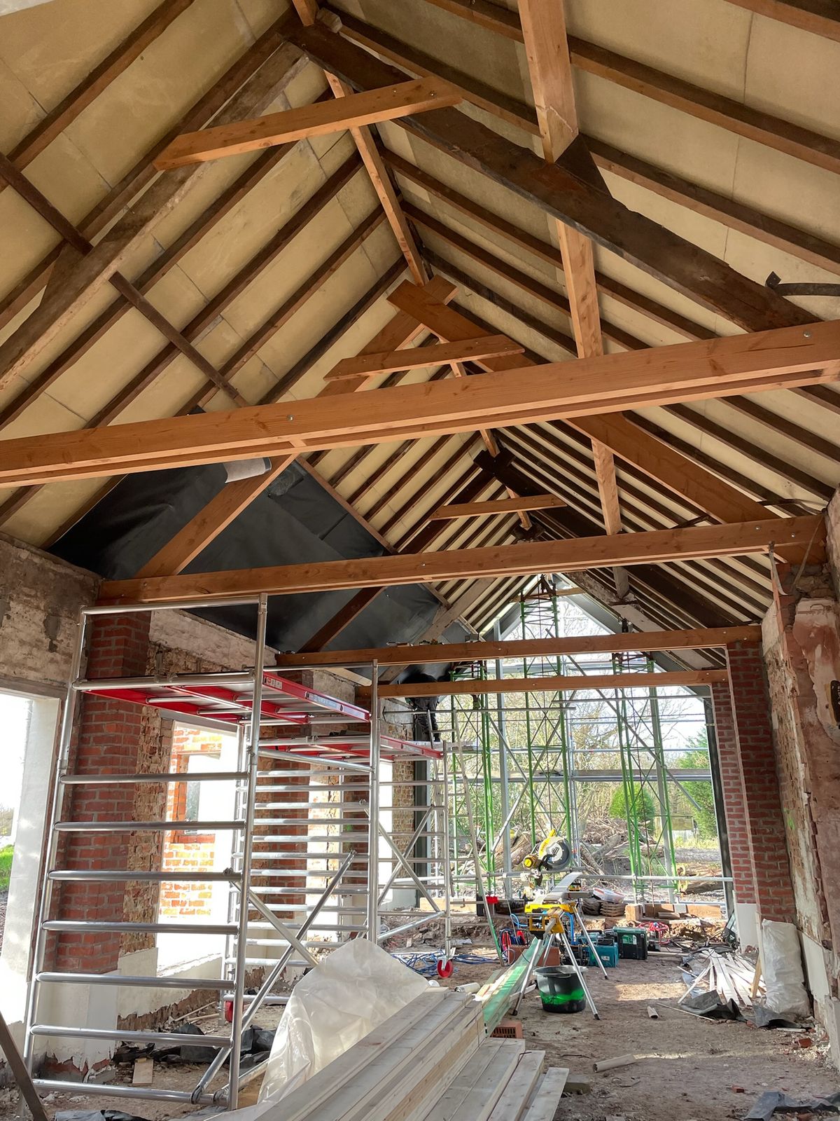 Houten dakbeschot boven de oude spanten van een schuur in renovatie in Eernegem.
