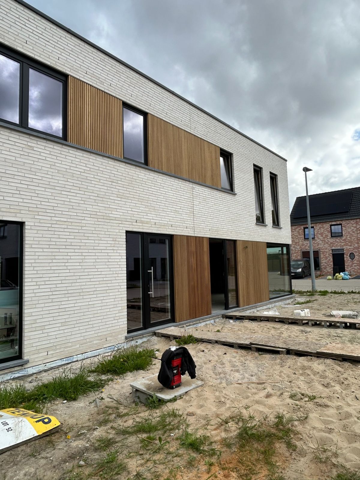 Witte bakstenen gevel met houten gevelbekleding op beide verdiepingen in Ardooie.