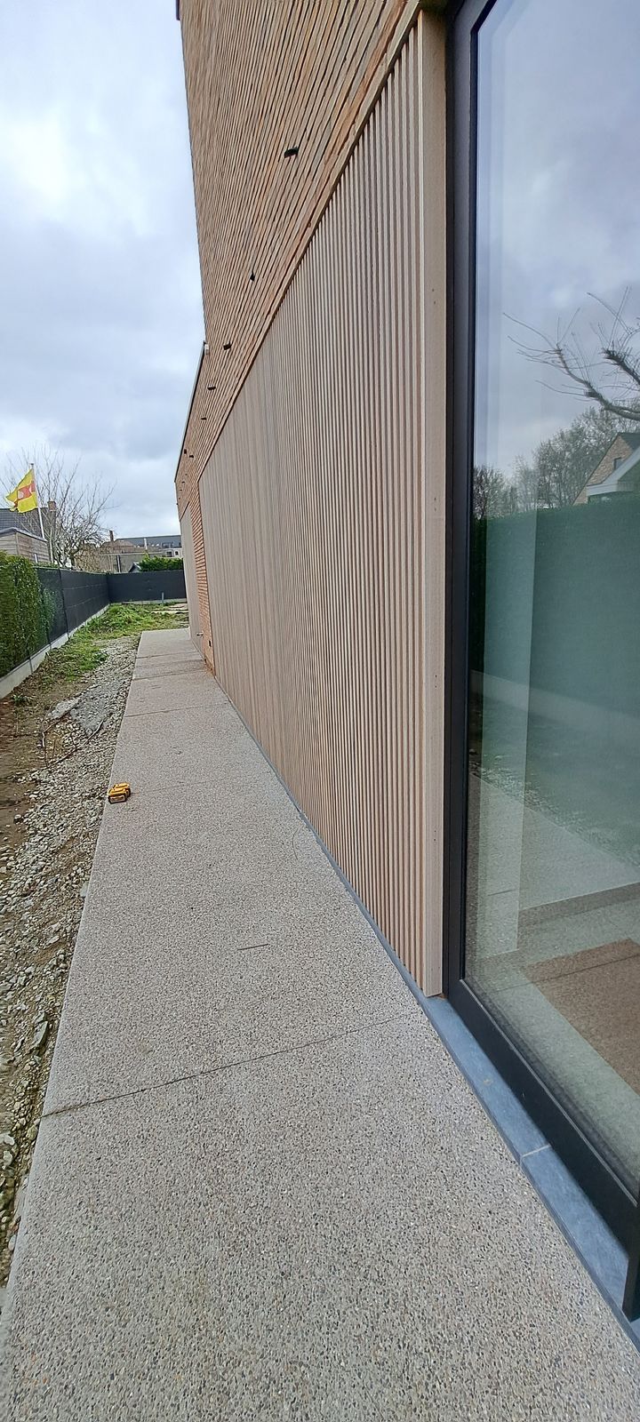Houten gevelbekleding in verticale latten langs een glazen pui in Knokke-Heist.