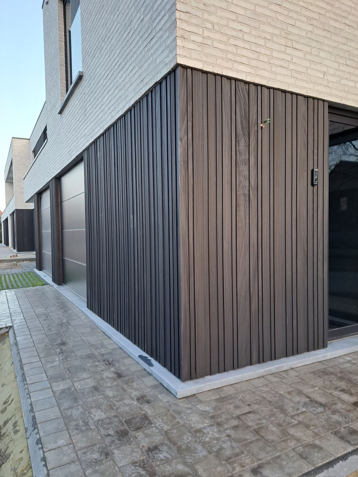 Donkere verticale houten gevelbekleding op de hoek van een woning in Lokeren.