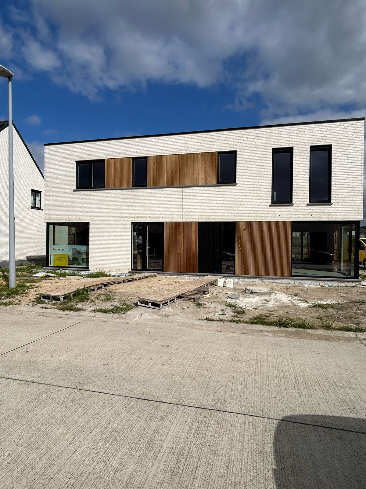 Vooraanzicht van nieuwbouwwoningen met houten gevelbekleding tussen de ramen in Ardooie.