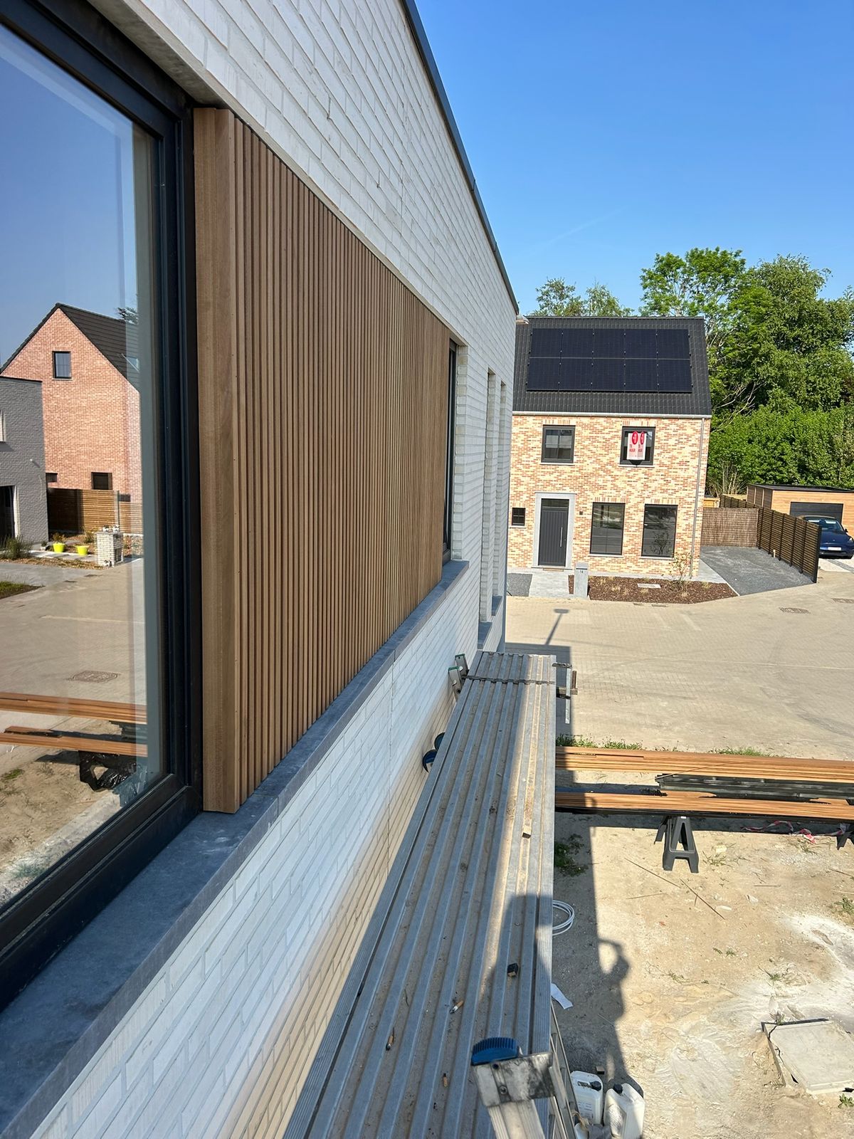 Houten gevelbekleding rond een groot raam op de gelijkvloerse verdieping in Ardooie.