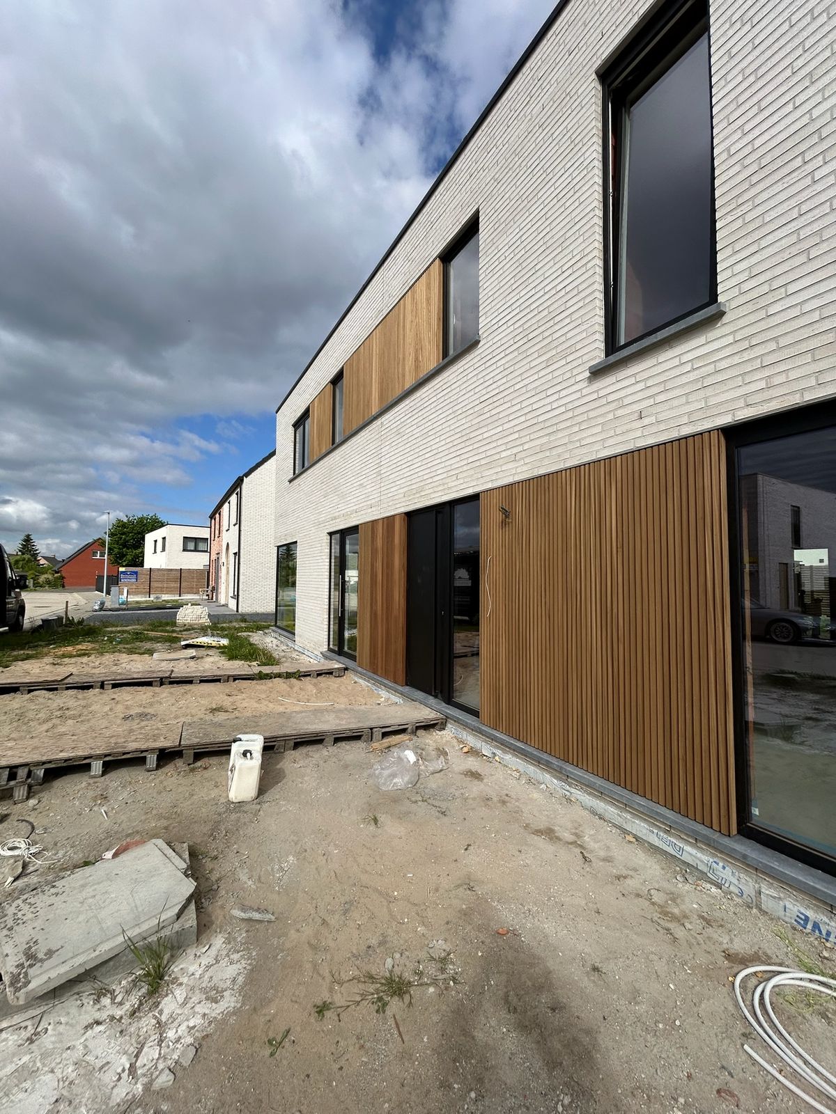 Houten gevelbekleding als accent op een nieuwbouw in witte baksteen in Ardooie.