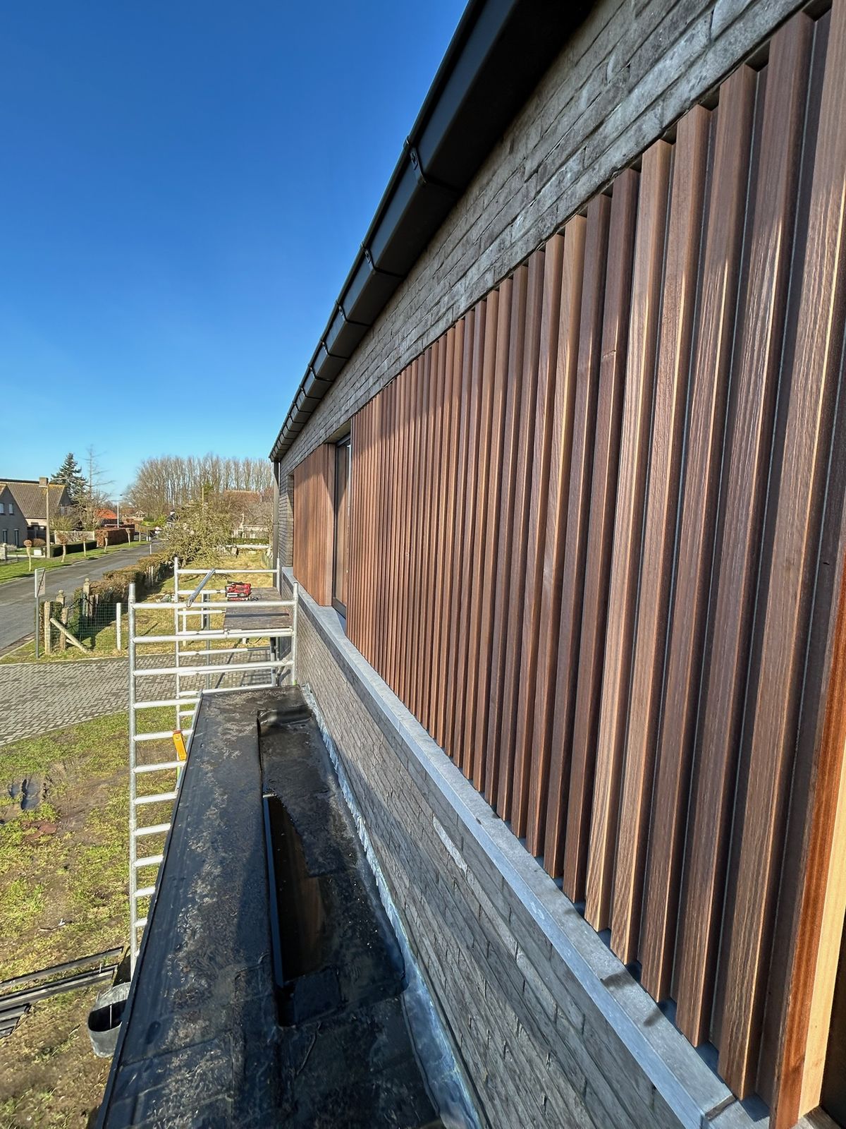Verticale houten gevelbekleding in latten op de bovenverdieping van een woning in Bassevelde.