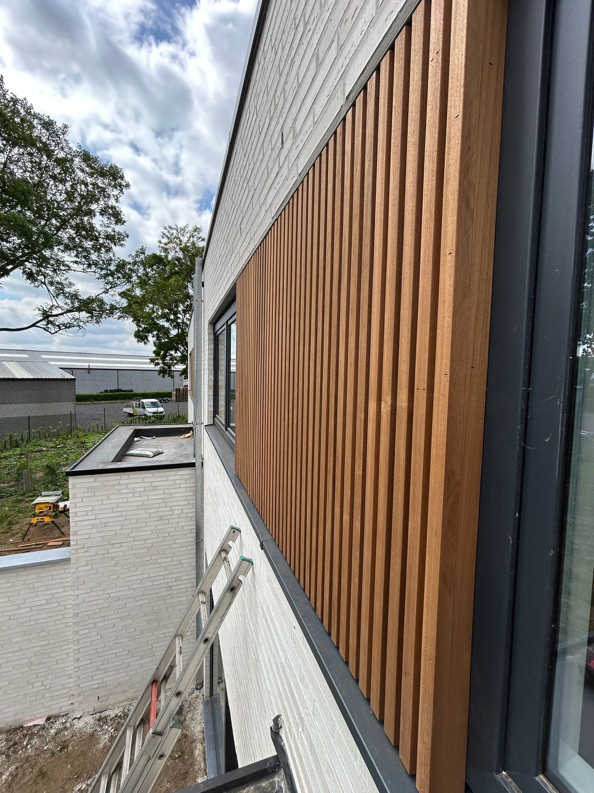 Houten gevelbekleding in latten naast een raam op de bovenverdieping van een woning in Beernem.