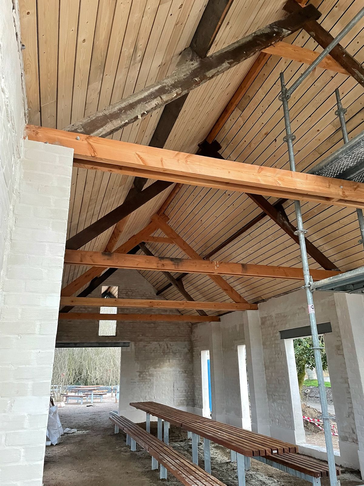 Houten plafond tussen oude dakspanten en balken in een gerenoveerde schuur in Eernegem.