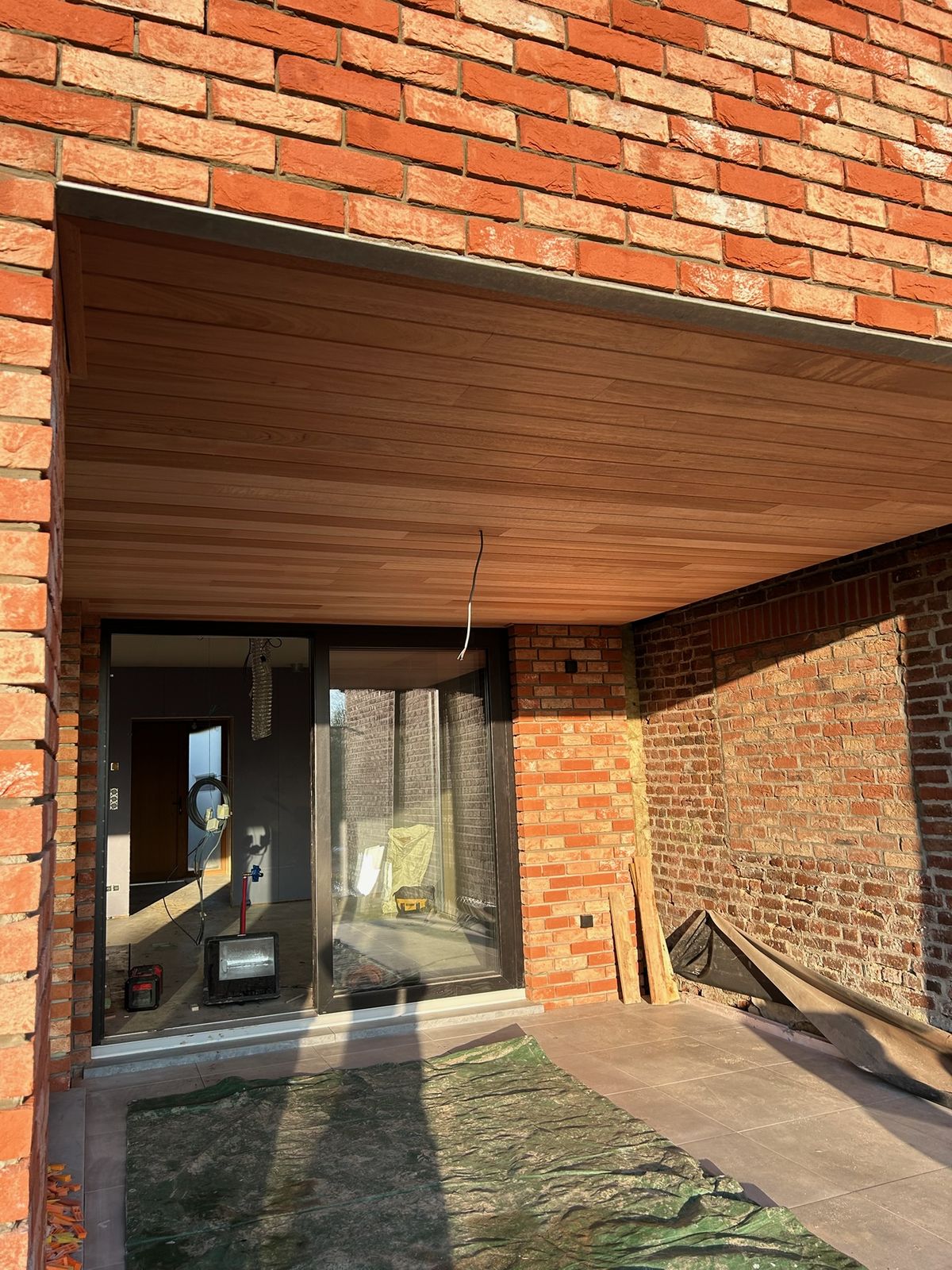 Houten plafond onder een overkapping bij de achtergevel van een bakstenen woning in Velm.