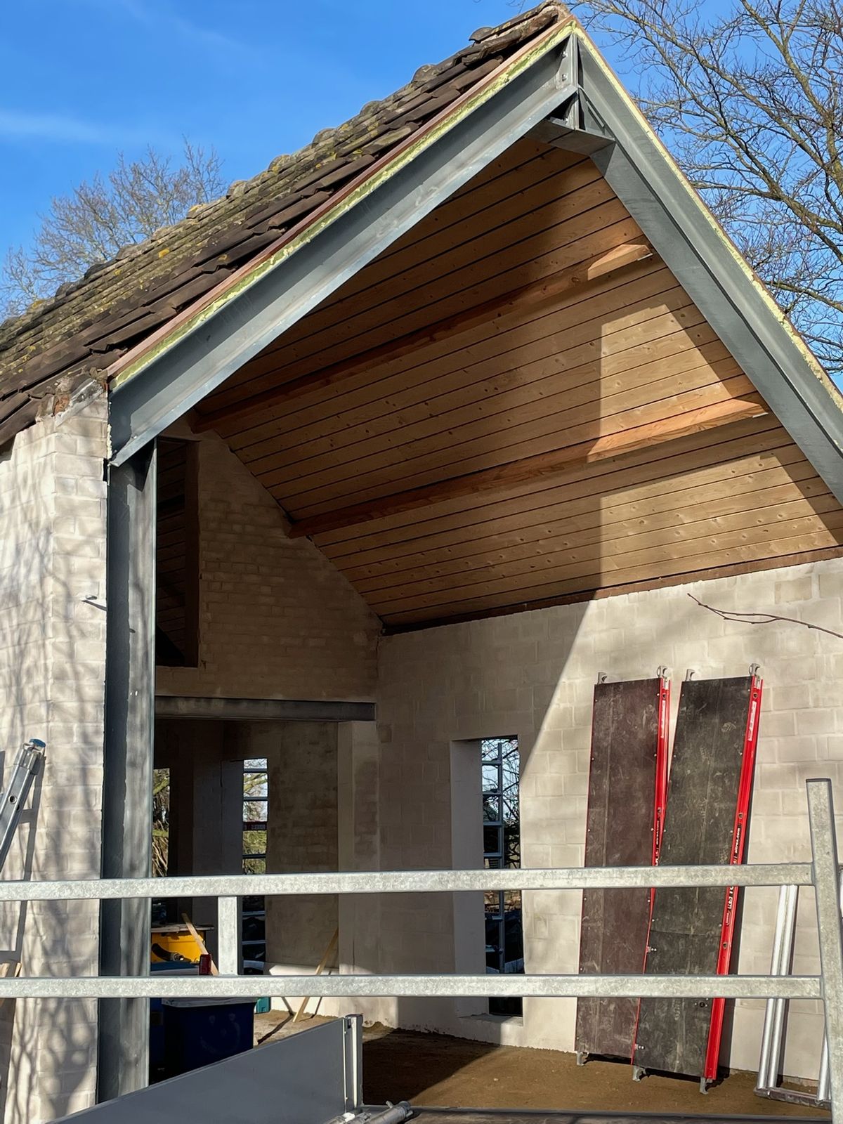 Oude schuur met nieuw houten plafond zichtbaar door de open puntgevel in Eernegem.