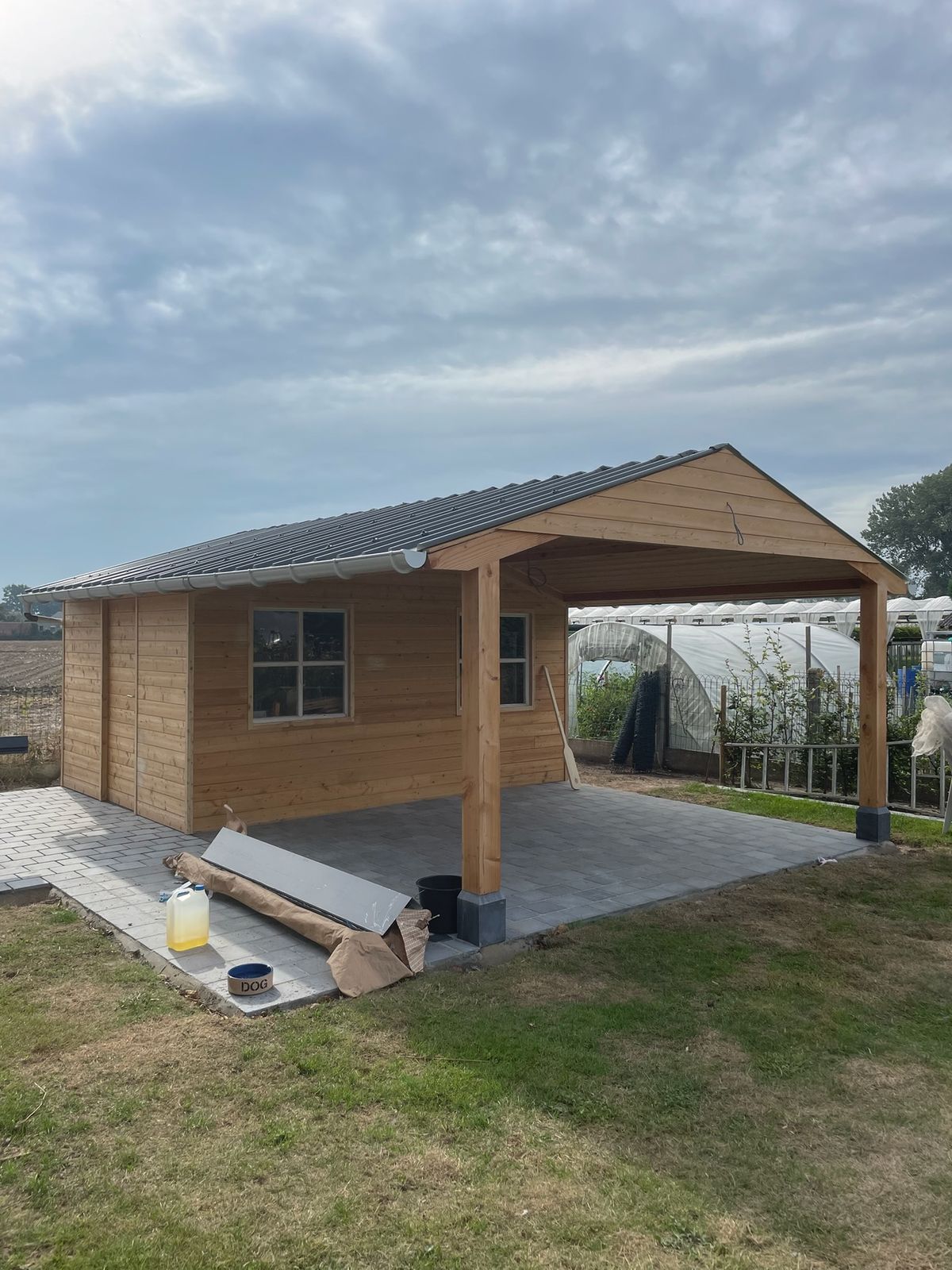 Houten poolhouse met overdekt terras en geklinkerde vloer in de tuin in Machelen.
