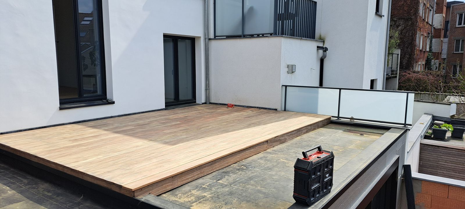 Nieuw houten terras op een dakterras naast een witte gevel in Gent.