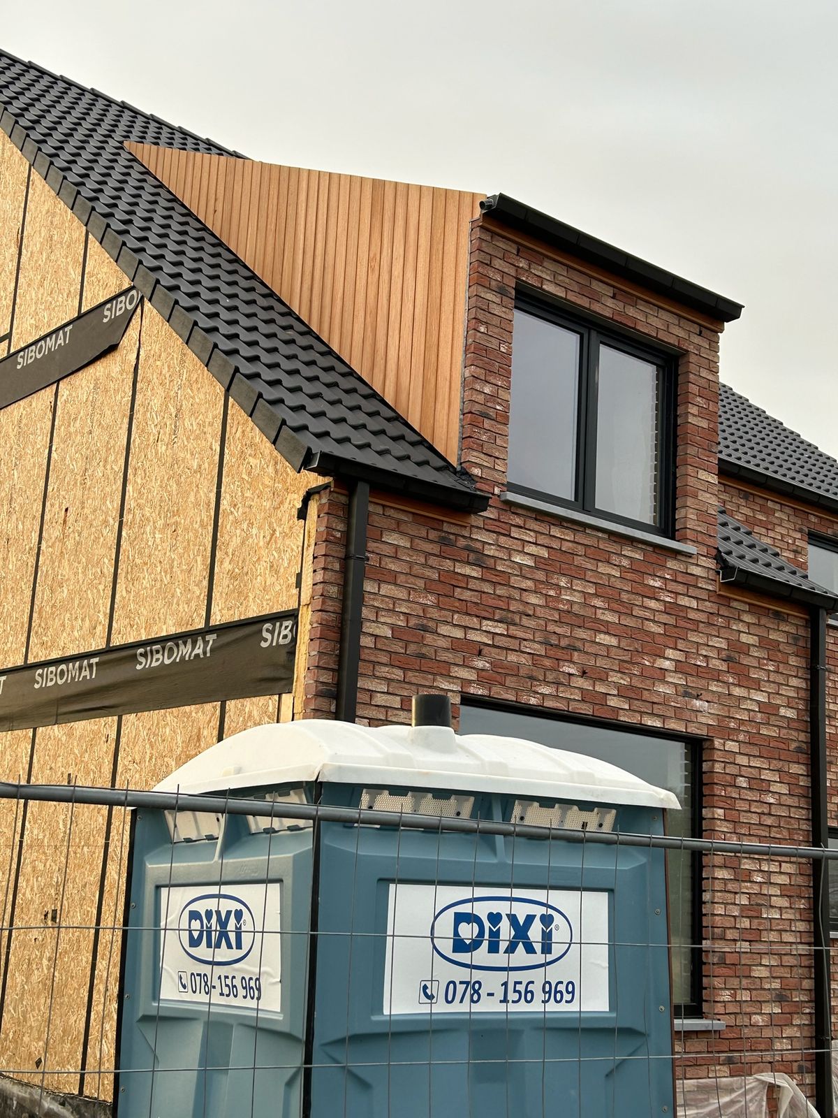 Houten bekleding van een dakkapel boven een rode bakstenen gevel in Varsenare.