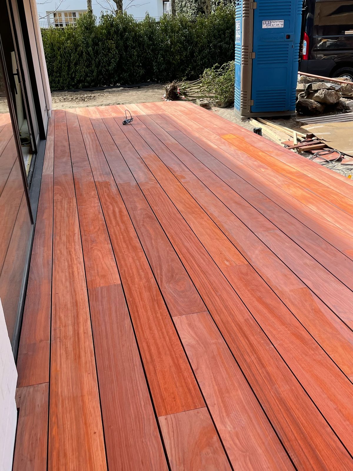 Lang hardhouten terras met strak gelegde planken langs de woning in Knokke-Heist.