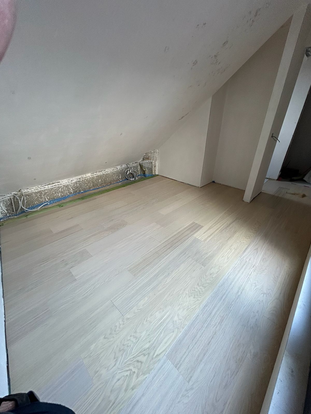 Lichte parketvloer in een zolderkamer onder schuin dak in een woning in Kortrijk.