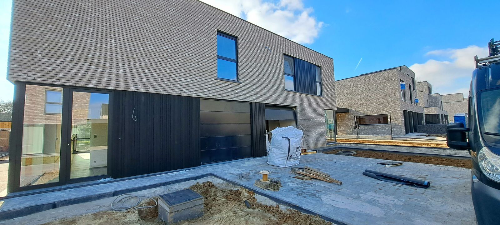 Nieuwbouwwoning met grijze baksteen en zwarte gevelbekleding op het gelijkvloers in Herzele.