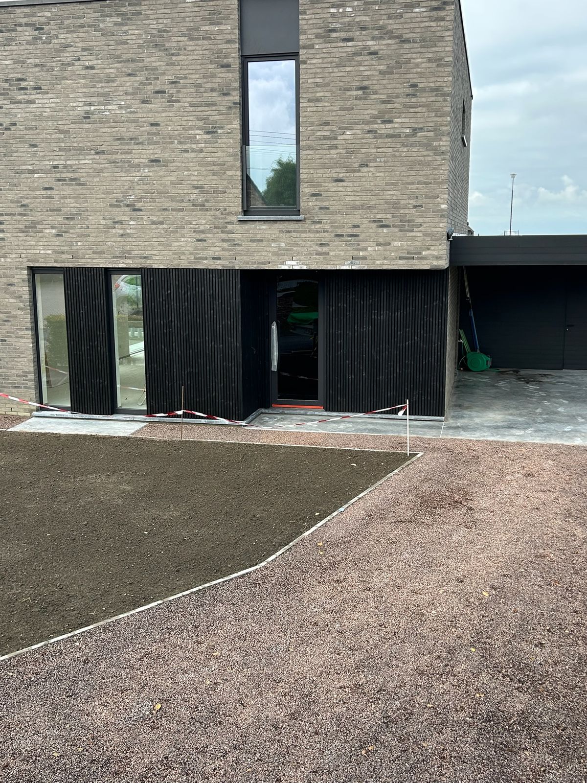 Nieuwbouwwoning met zwarte houten gevelbekleding en grijze baksteen in Wijnendale.
