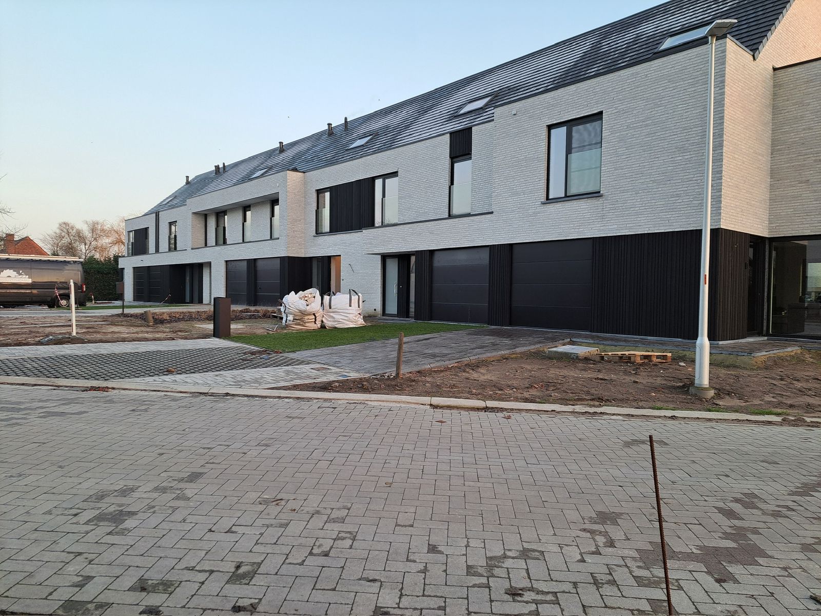 Rij nieuwbouwwoningen met donkere houten gevelbekleding op het gelijkvloers in Lokeren.
