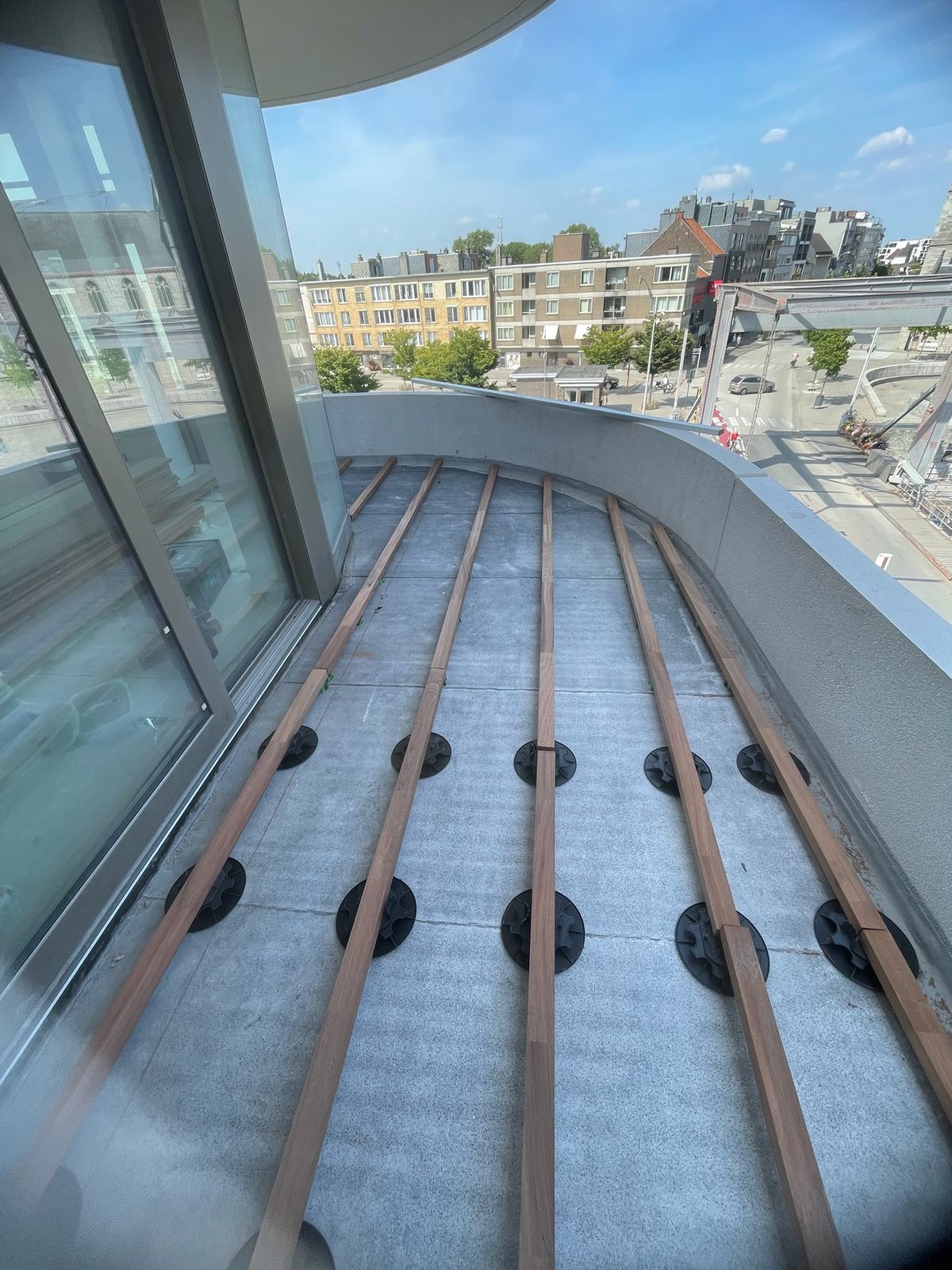 Houten draagbalken op terrasdragers als onderstructuur voor een gebogen dakterras in Deinze.