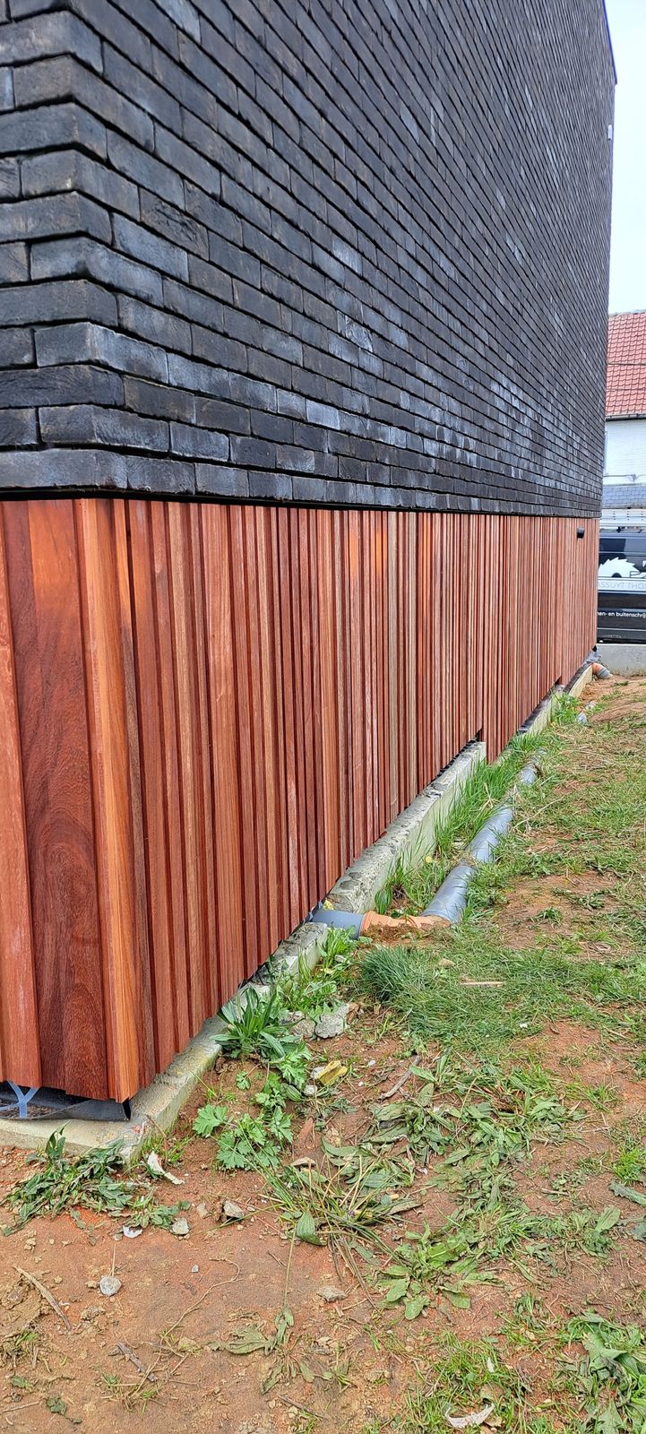 Padoek gevelbekleding in verticale planken onder een donkere leien gevel in Wintam.