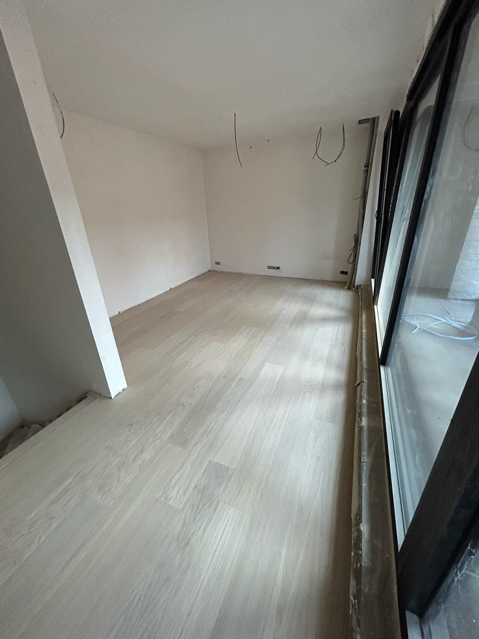 Lichte parketvloer gelegd in een kamer met grote ramen in Kortrijk