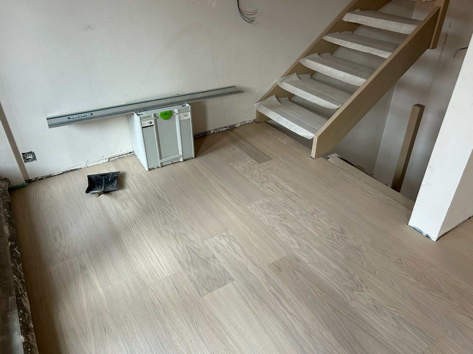 Lichte parketvloer gelegd op de zolderverdieping naast een open trap in Kortrijk.