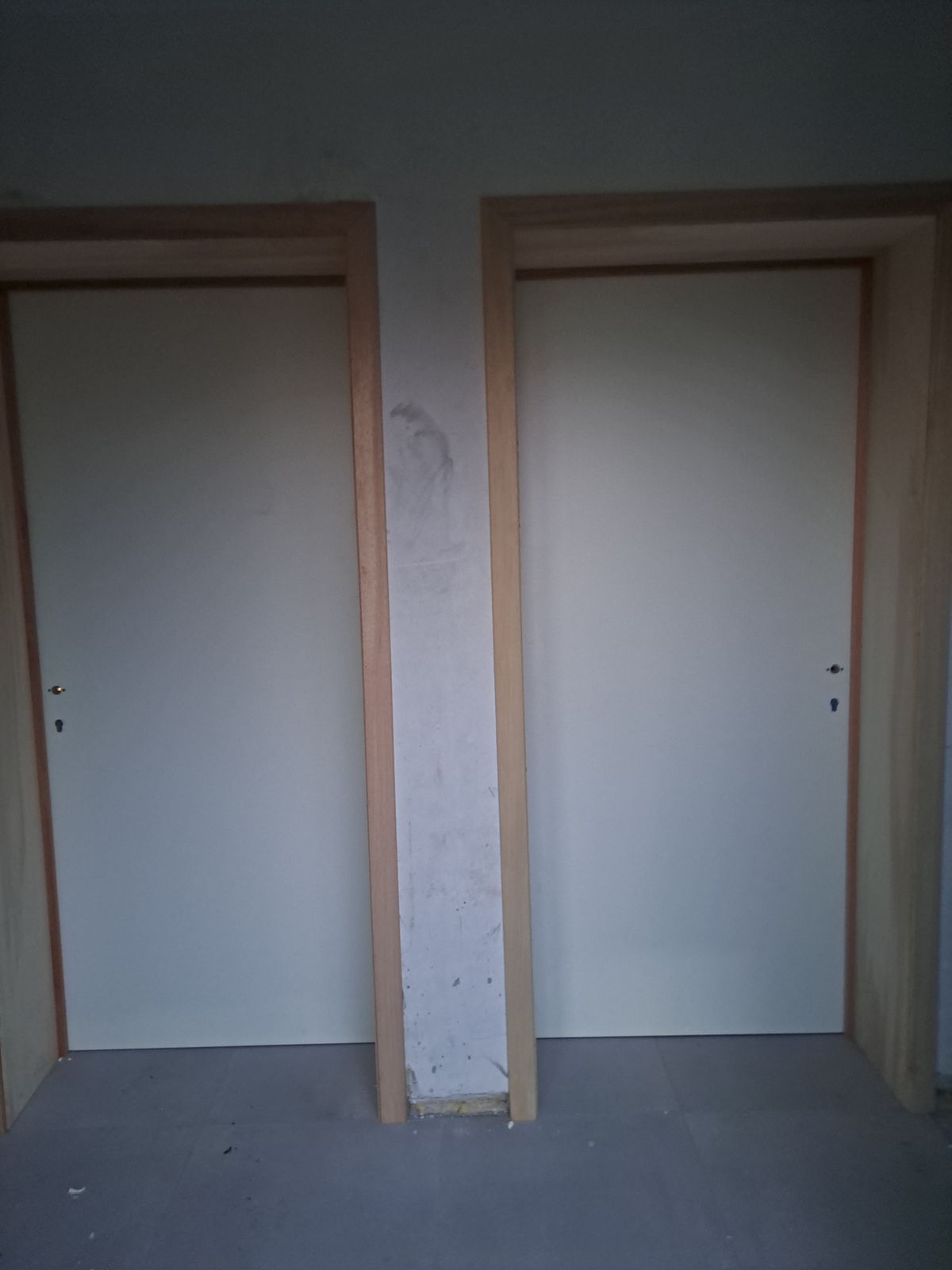 Twee witte binnendeuren naast elkaar met houten deurkaders in een woning in Hamme.