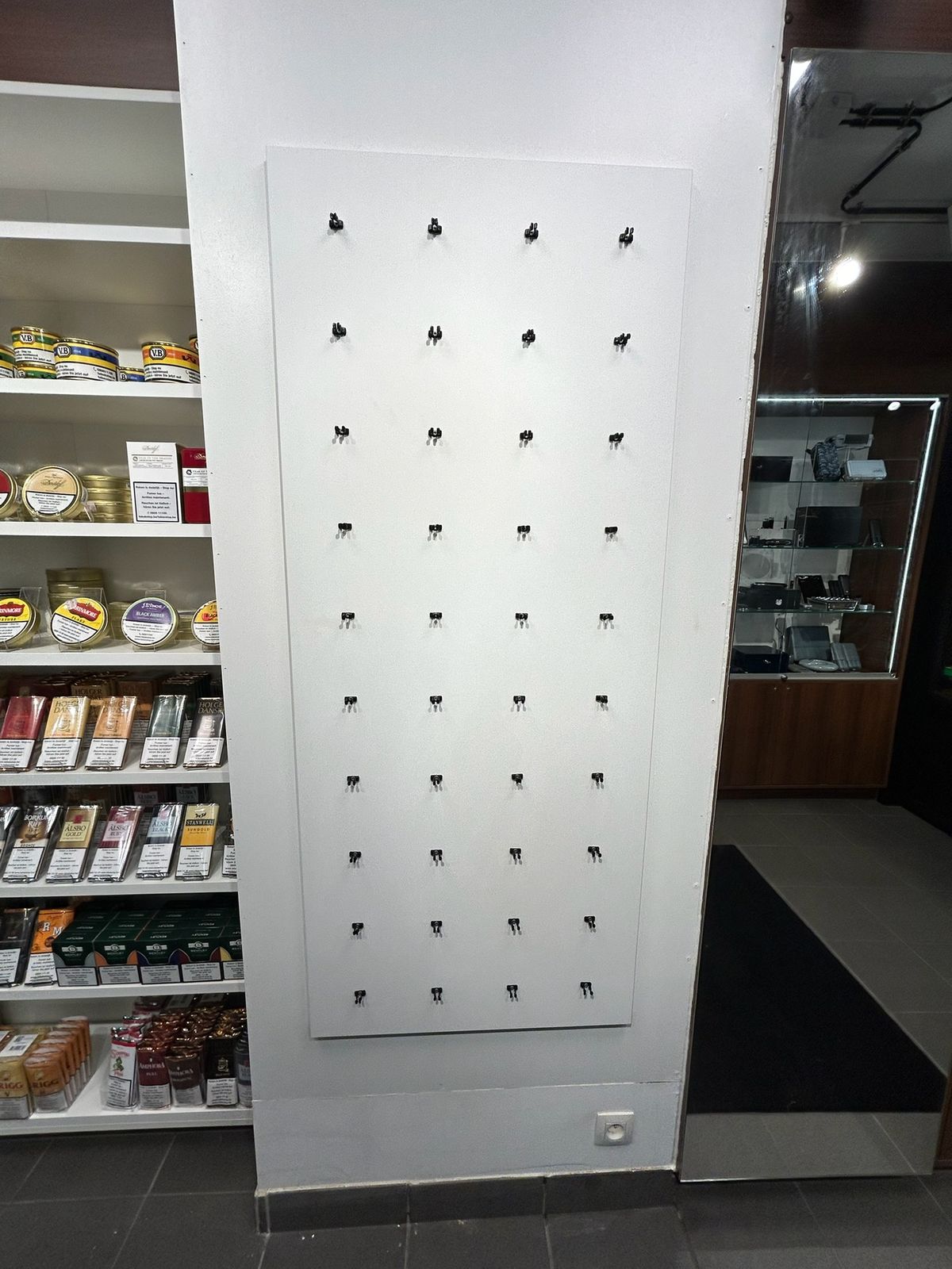 Winkelinrichting op maat met wit wandpaneel en rekken met producten in Knokke-Heist.