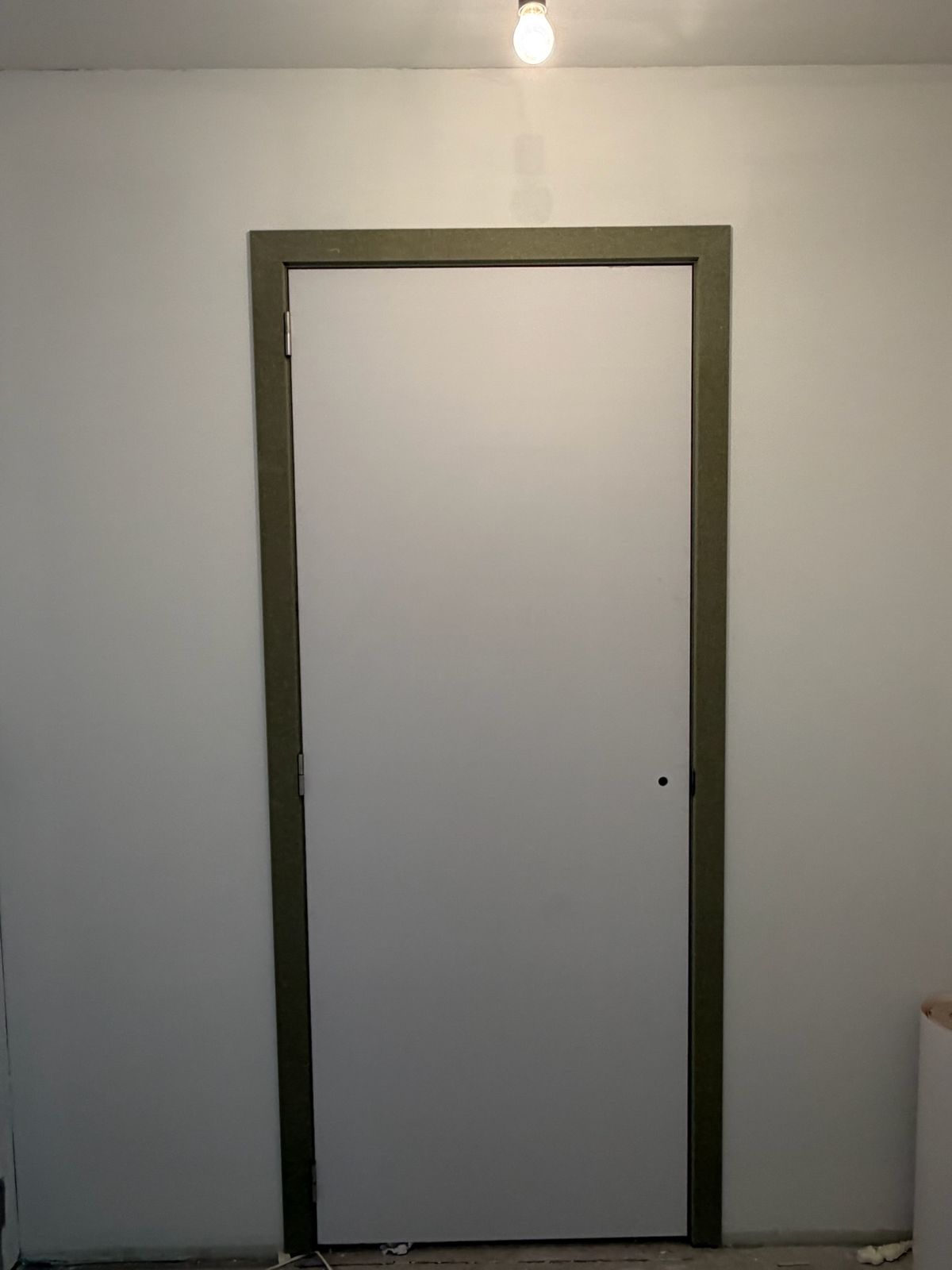 Witte binnendeur met donkergroen deurkader in een pas gezette wand in Nieuwpoort.
