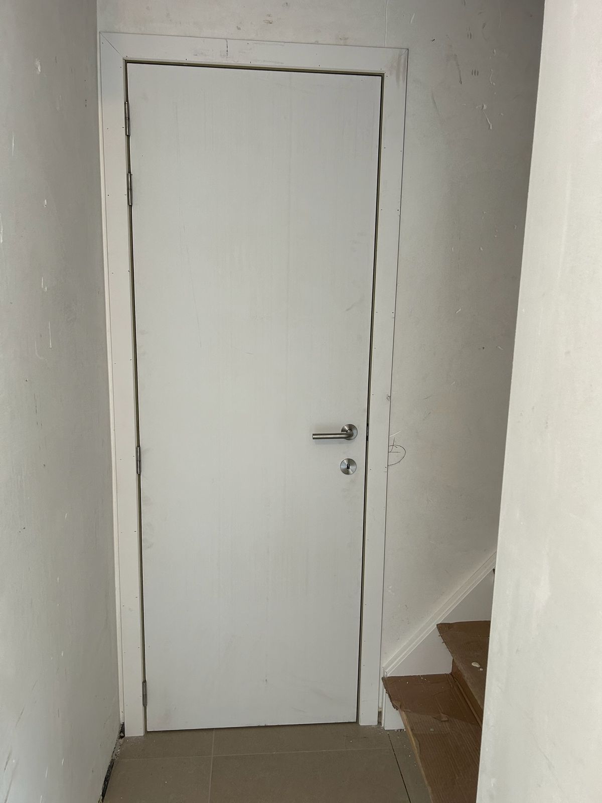Witte binnendeur met inox klink aan het einde van een hal in Wildenburg.