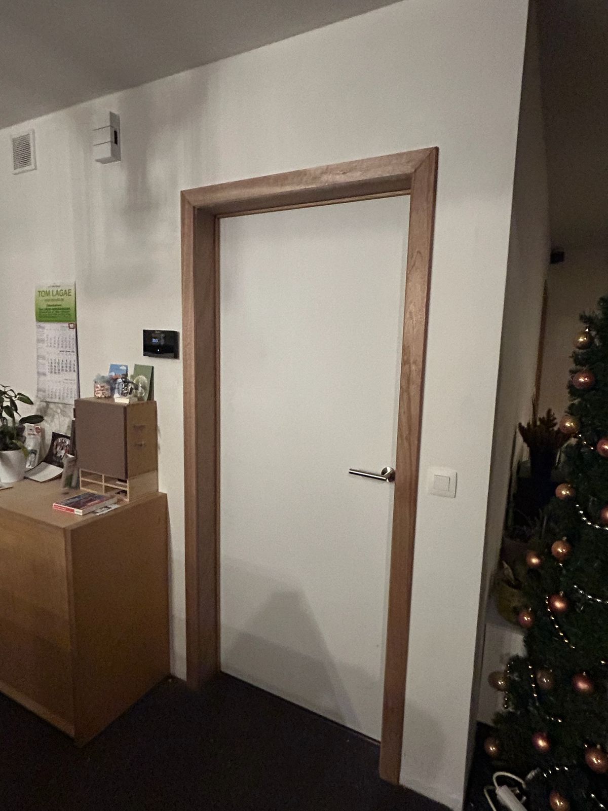 Witte binnendeur met donkere houten deuromlijsting in een woonruimte in Lendelede.