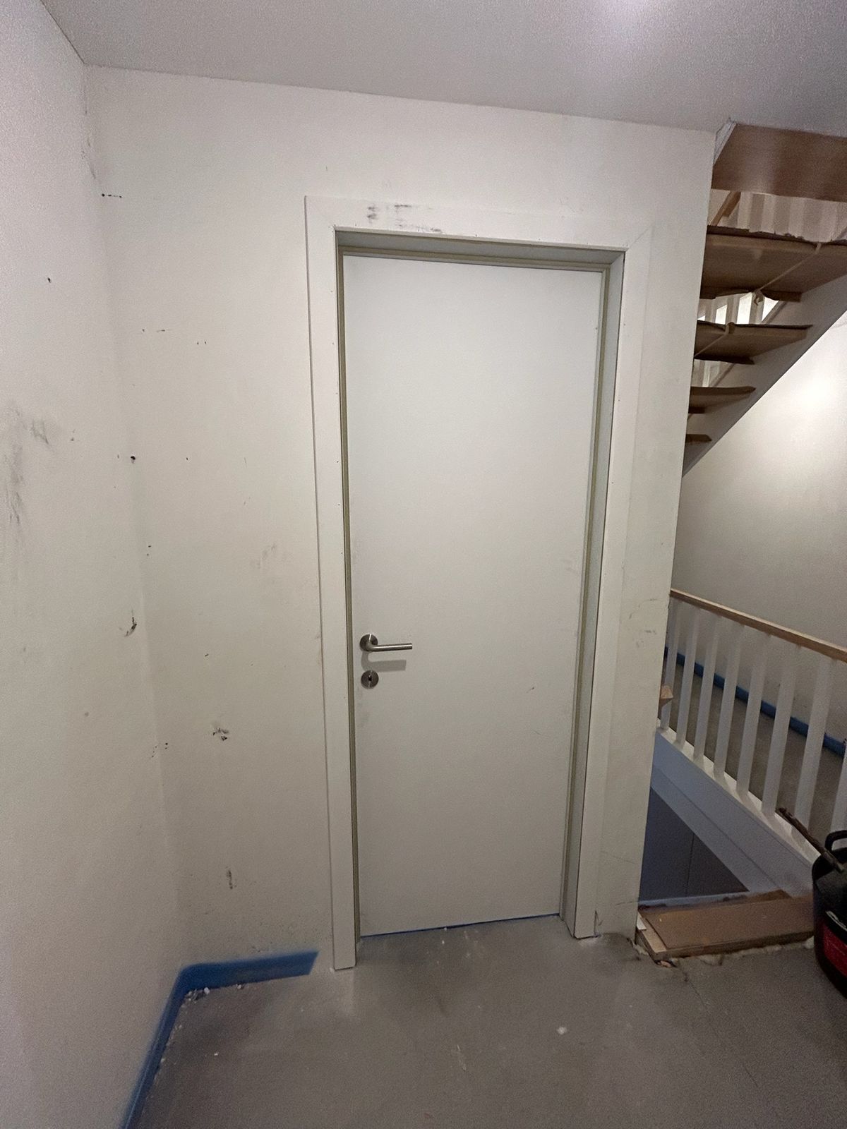 Witte binnendeur met omlijsting in een traphal van een woning in Wildenburg.