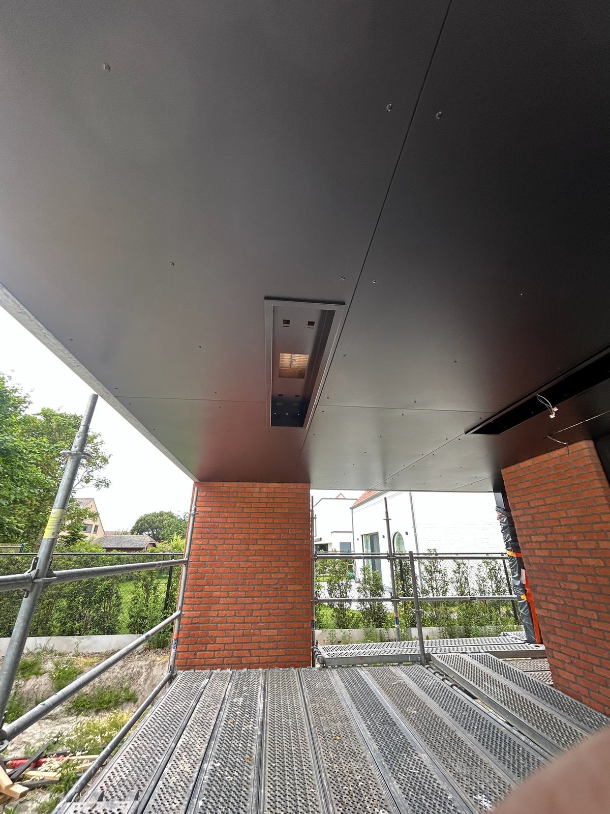 Zwart buitenplafond boven een overdekt terras in Vlissegem.