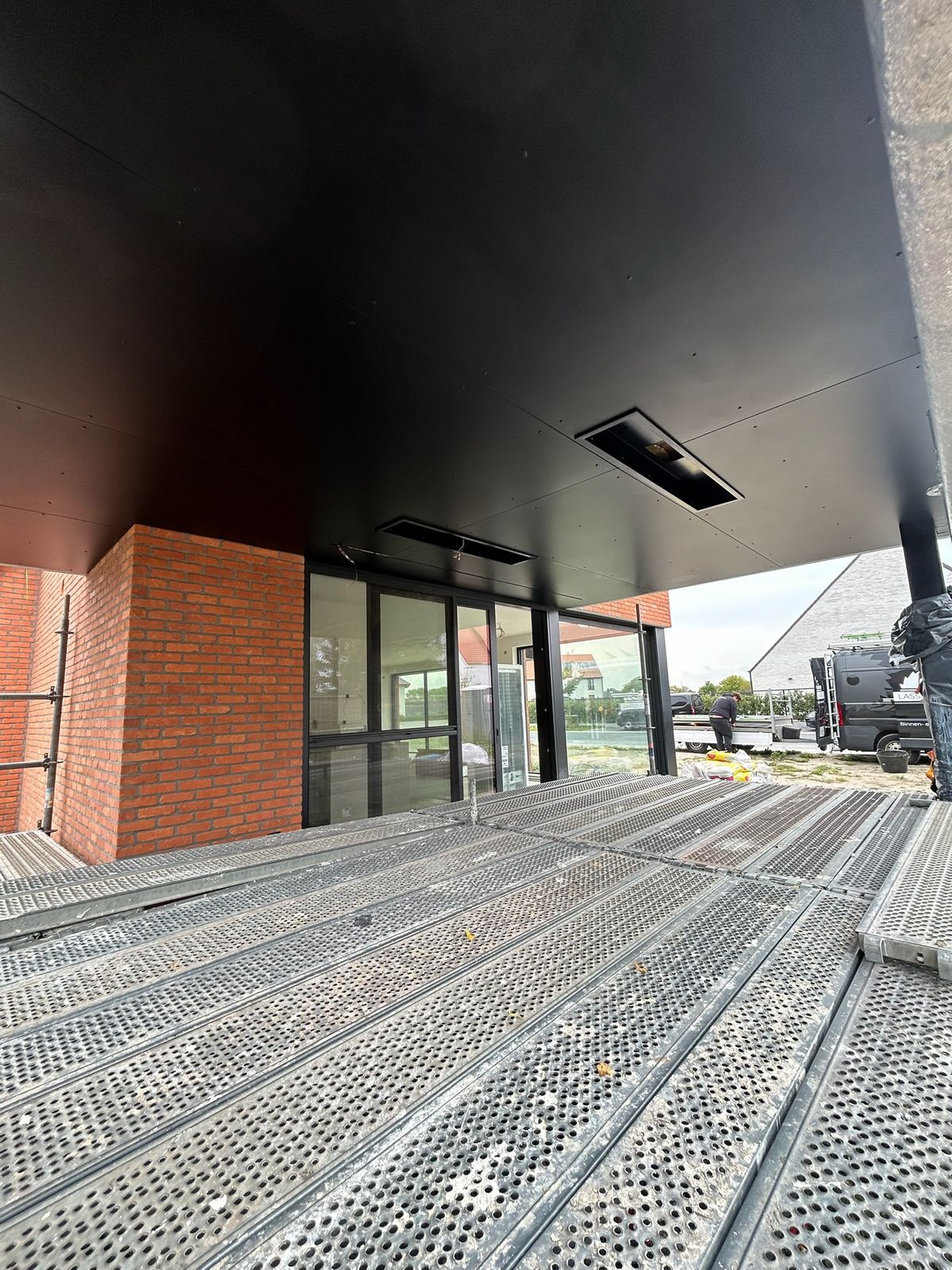 Overkapping met strak zwart buitenplafond en inbouwspots boven het terras in Vlissegem.